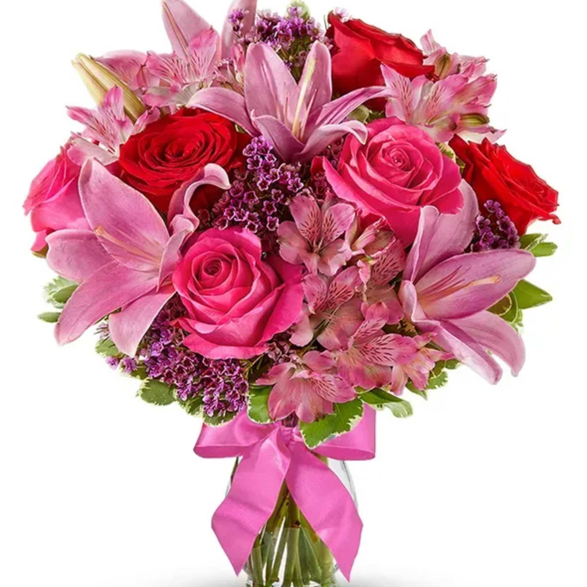 Pink and red roses with lilies in a glass vase tied with a pink ribbon.