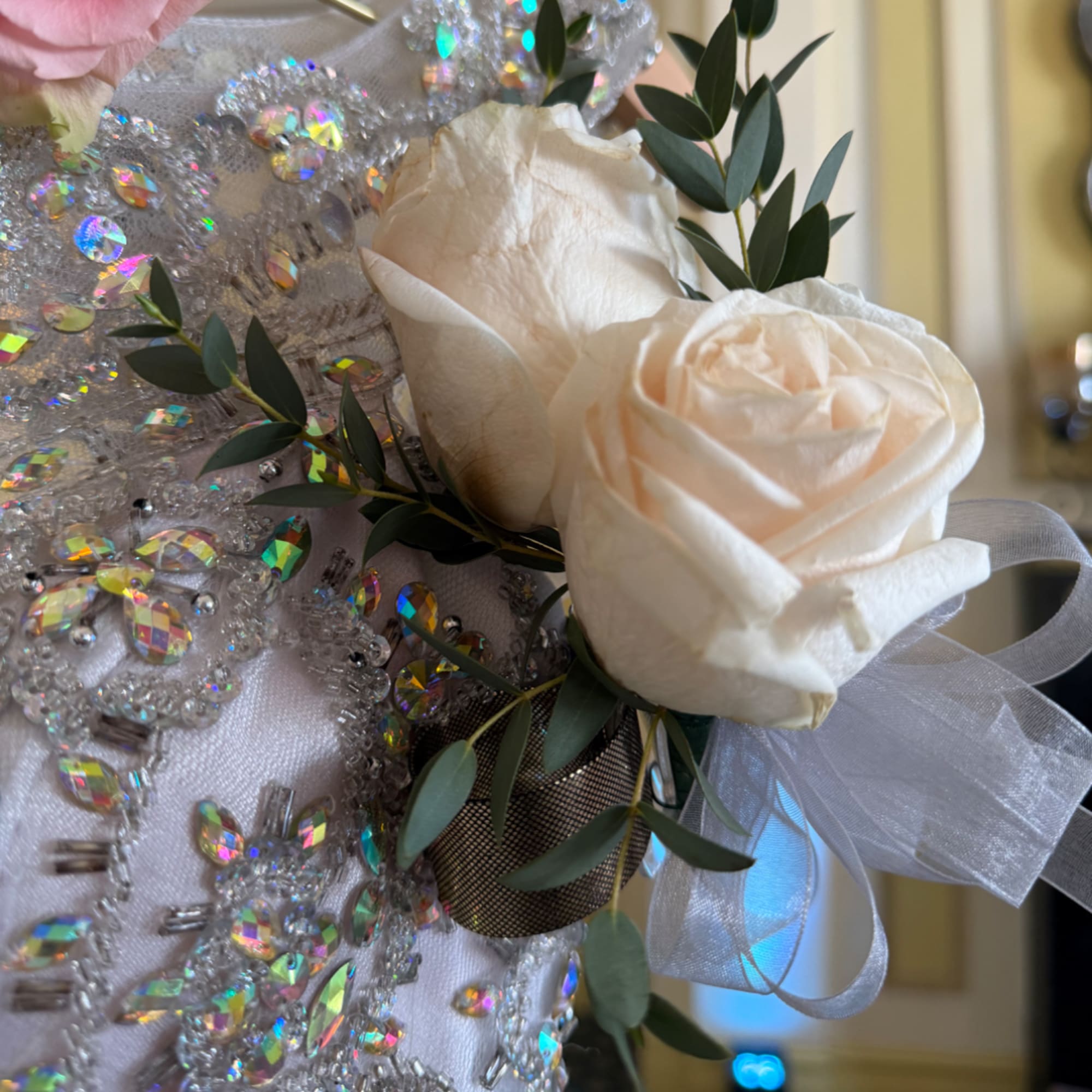 White rose corsage with green leaves and a sheer ribbon