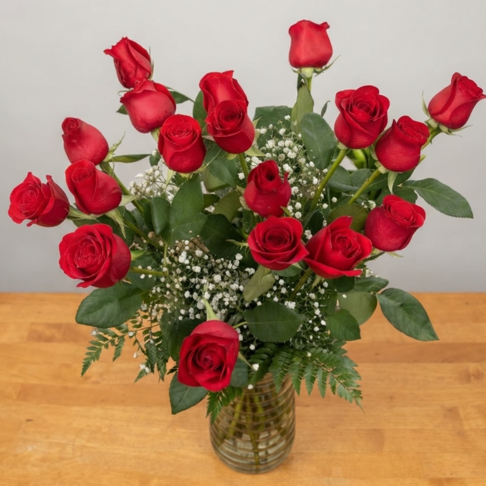 Red roses arranged in a clear glass vase with baby's breath, photo 2 of 2
