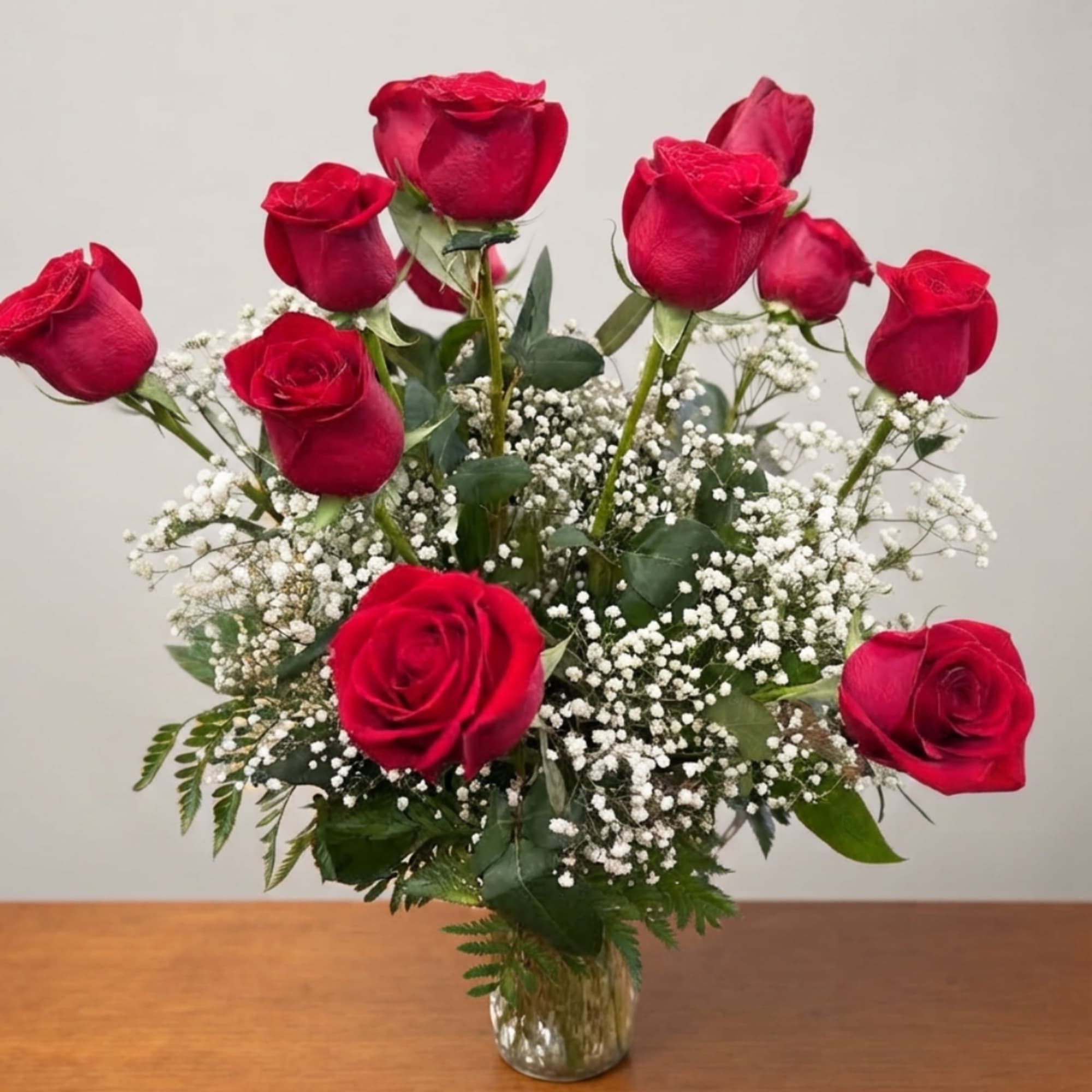 Red roses arranged in a clear glass vase with white baby's breath, photo 3 of 3