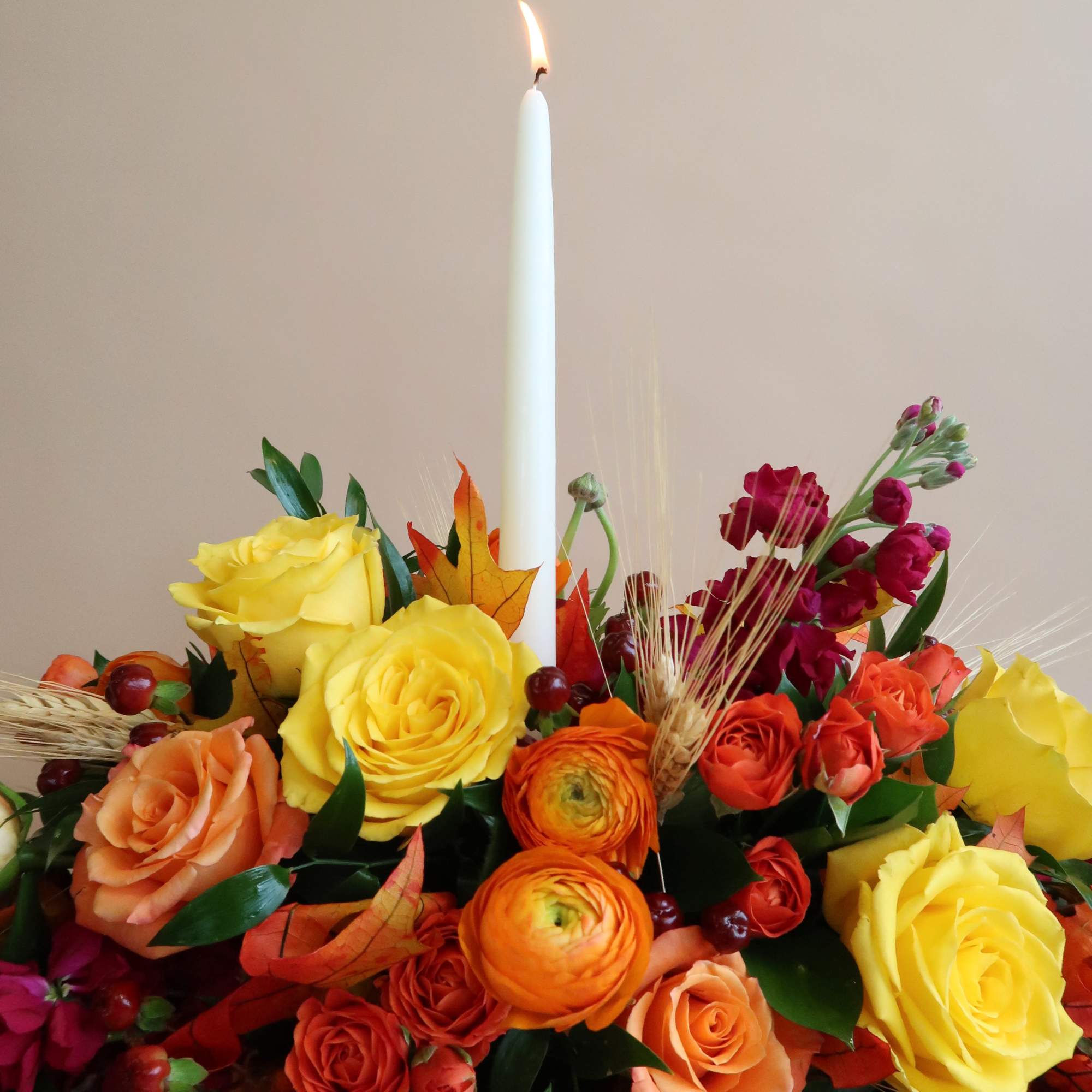 Colorful rose arrangement with a lit white candle in the center