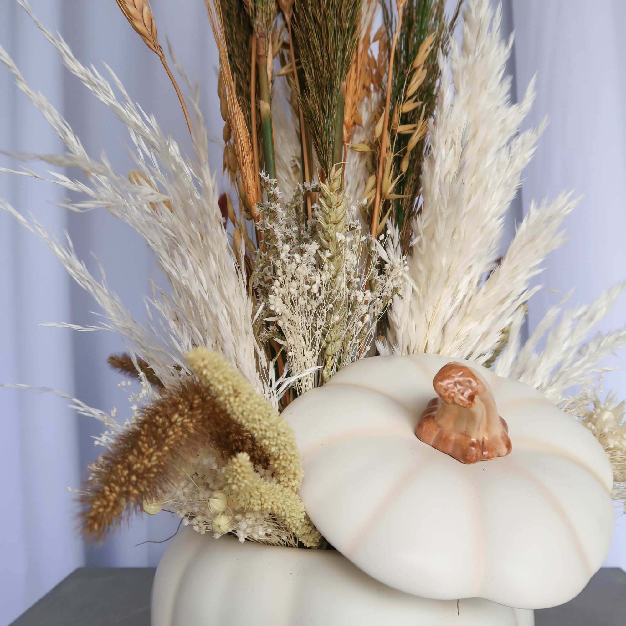 Dried grasses arranged in a white pumpkin-shaped vase