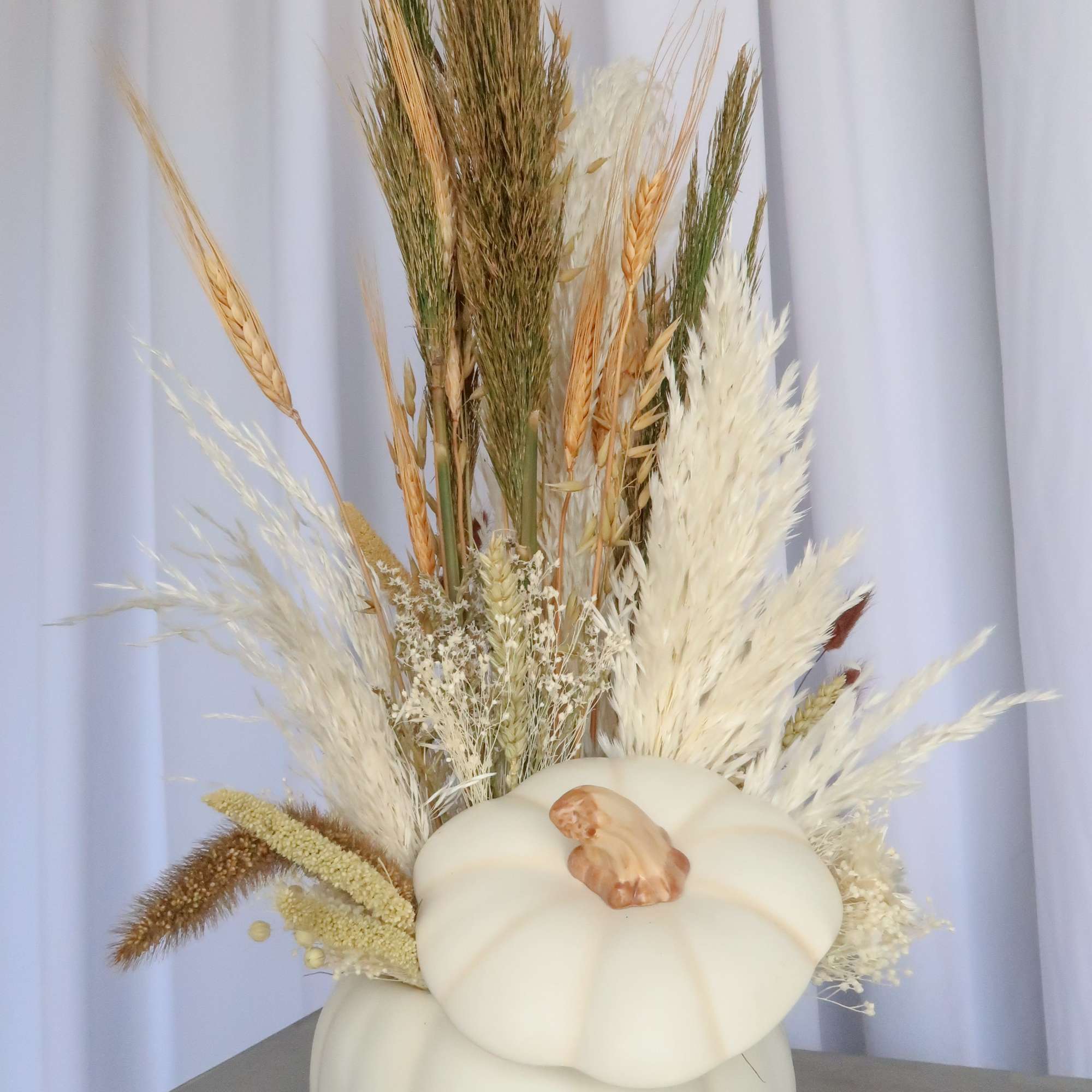 White pumpkin vase filled with dried grasses and wheat