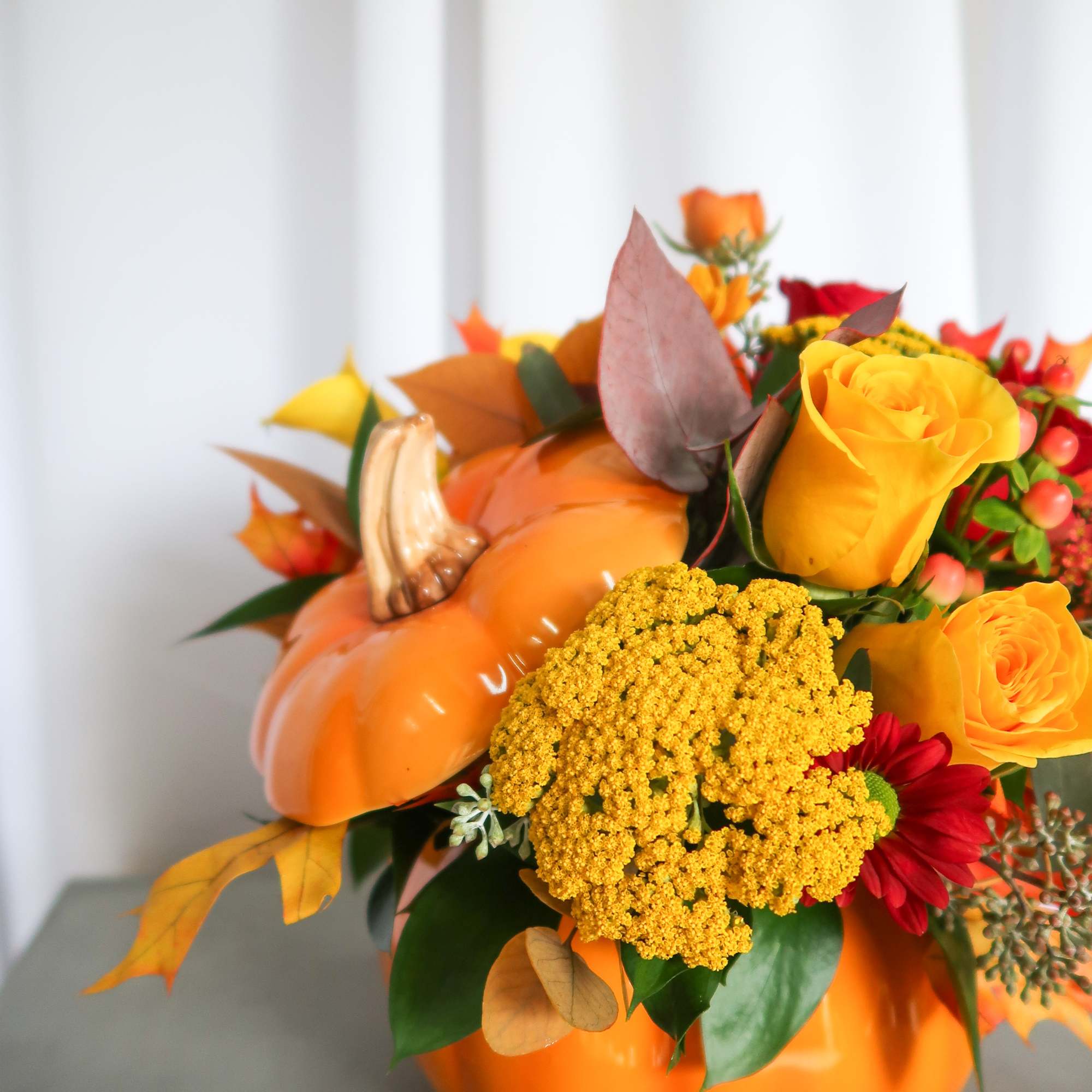 Orange pumpkin-shaped arrangement with yellow and red flowers