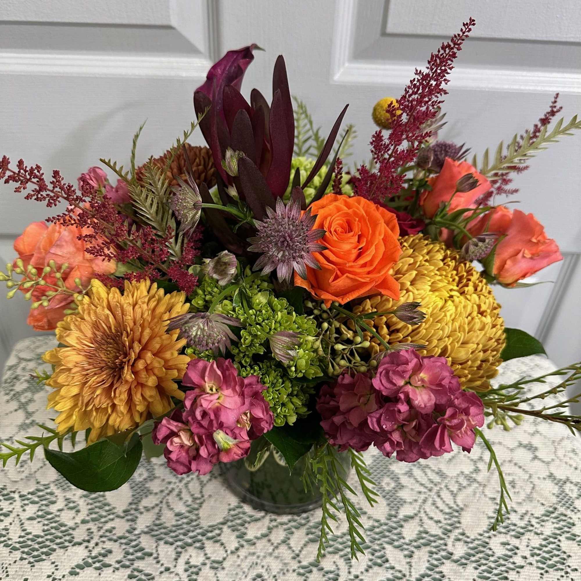 Mixed bouquet in a glass vase with orange, yellow, and pink flowers