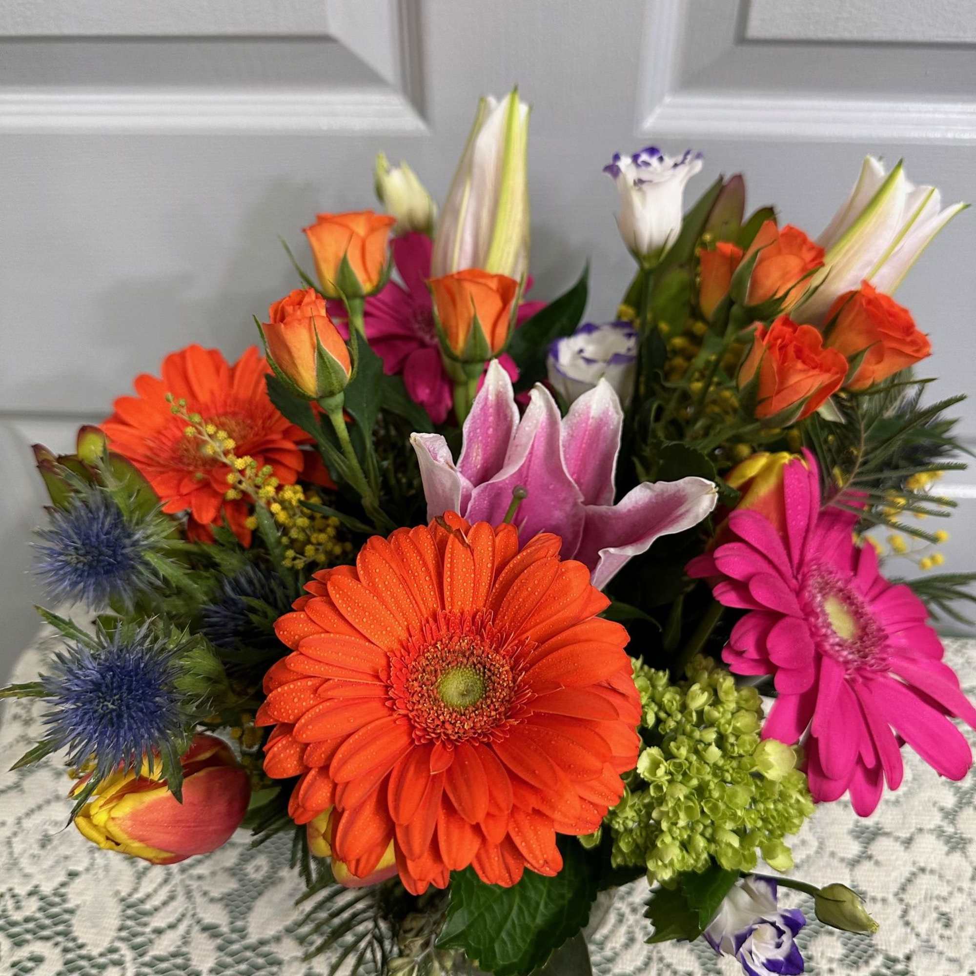 Bright mixed bouquet with orange gerberas, roses, lilies, and pink blooms