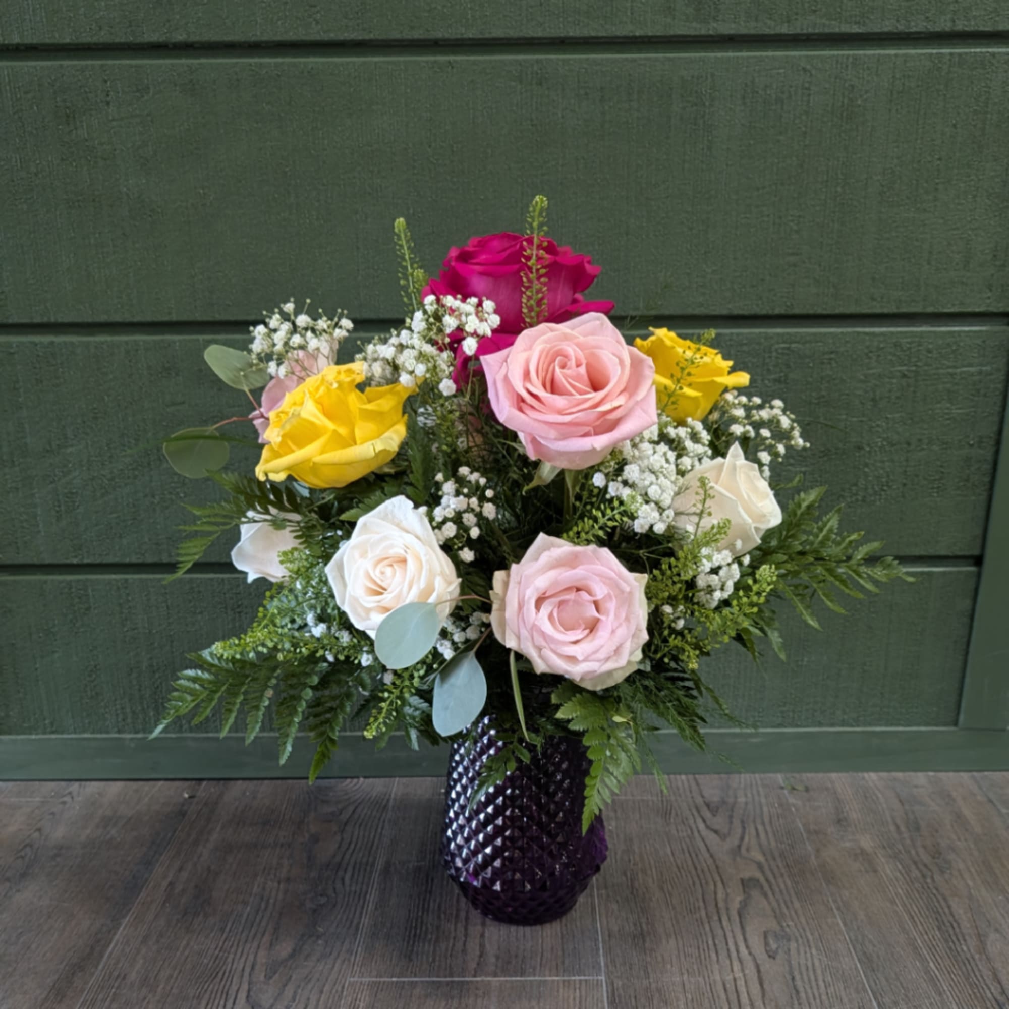 Mixed roses in a purple vase with baby's breath