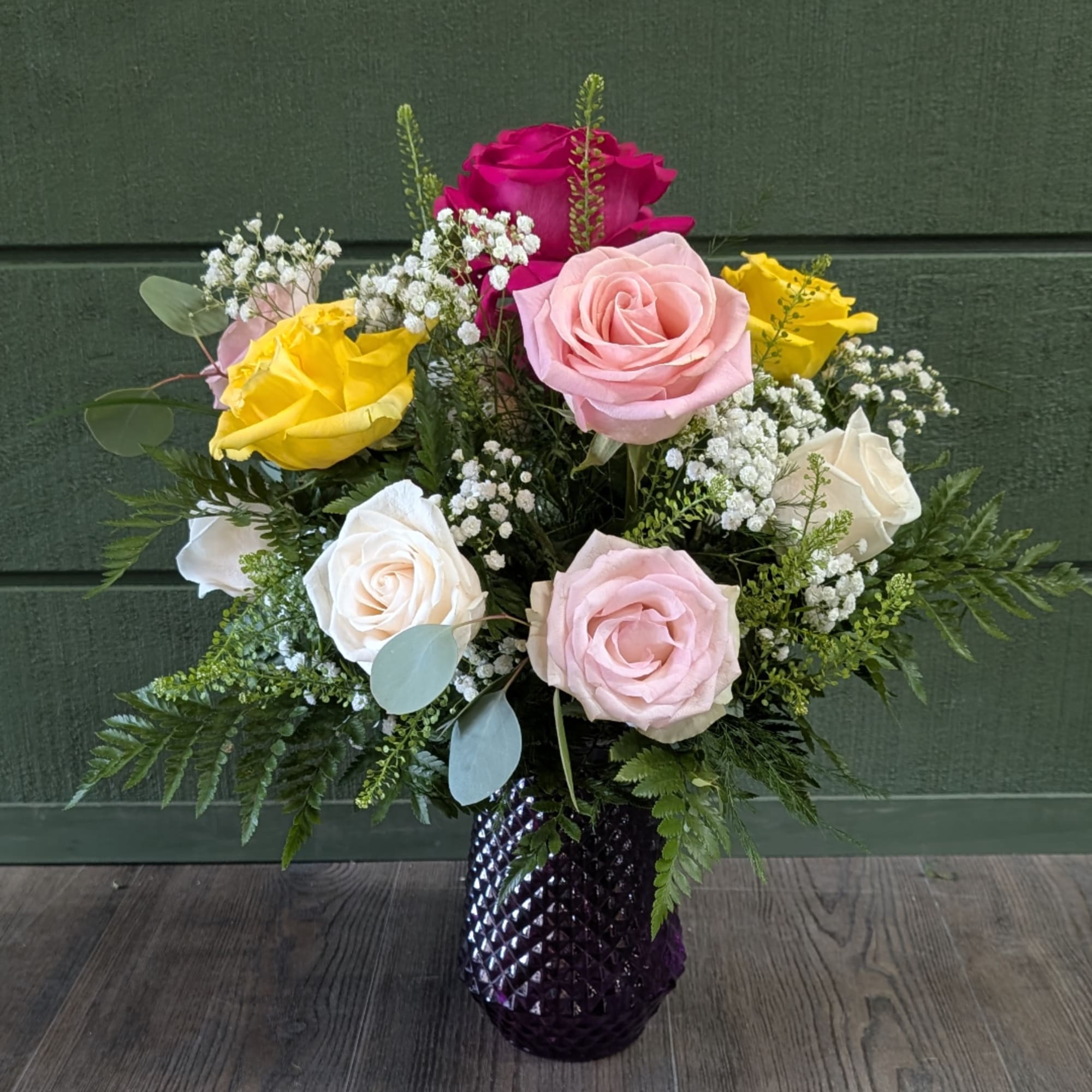 Mixed roses in a purple vase with baby's breath