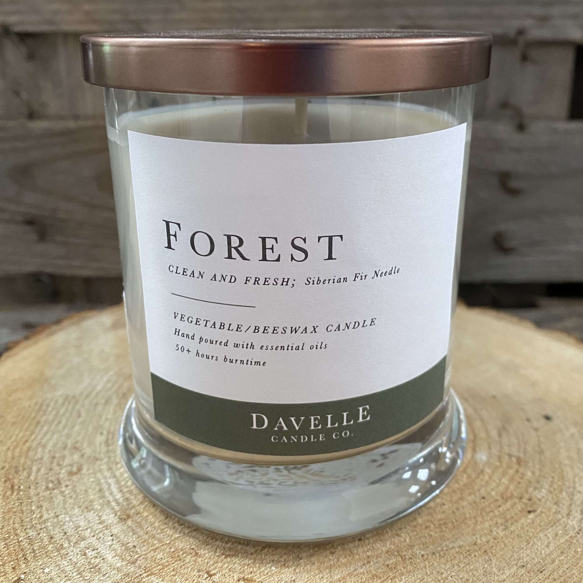 Glass jar candle with a copper lid and forest label