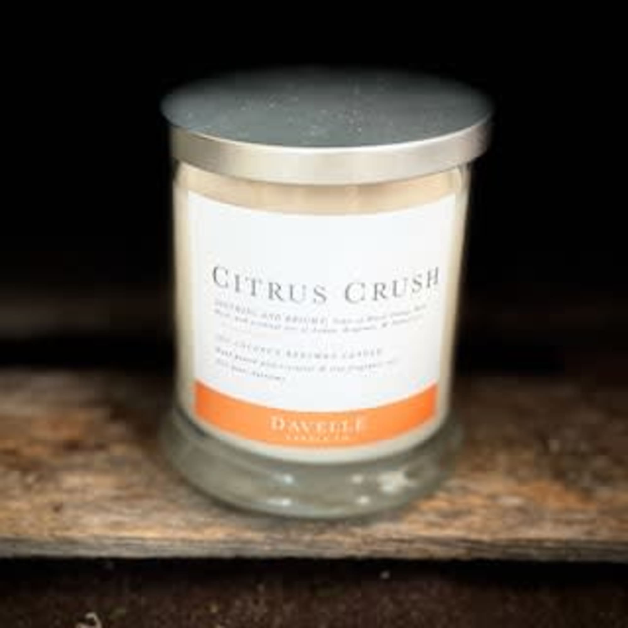 A glass jar candle labeled Citrus Crush with a metal lid.
