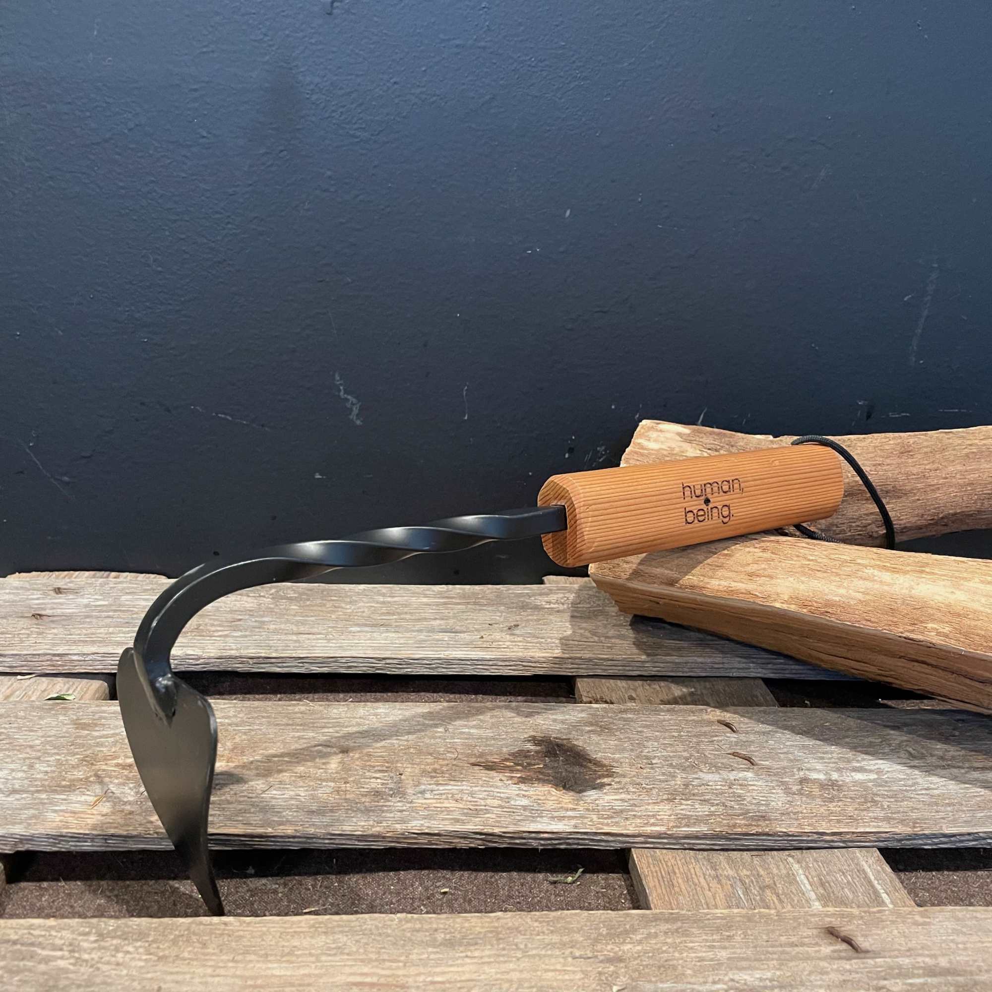 Black metal garden tool with a wooden handle on stacked wood