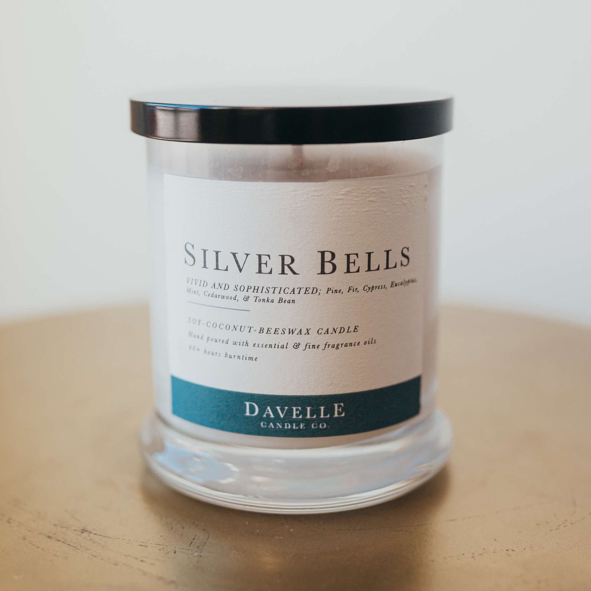 A scented candle in a clear glass jar with a black lid