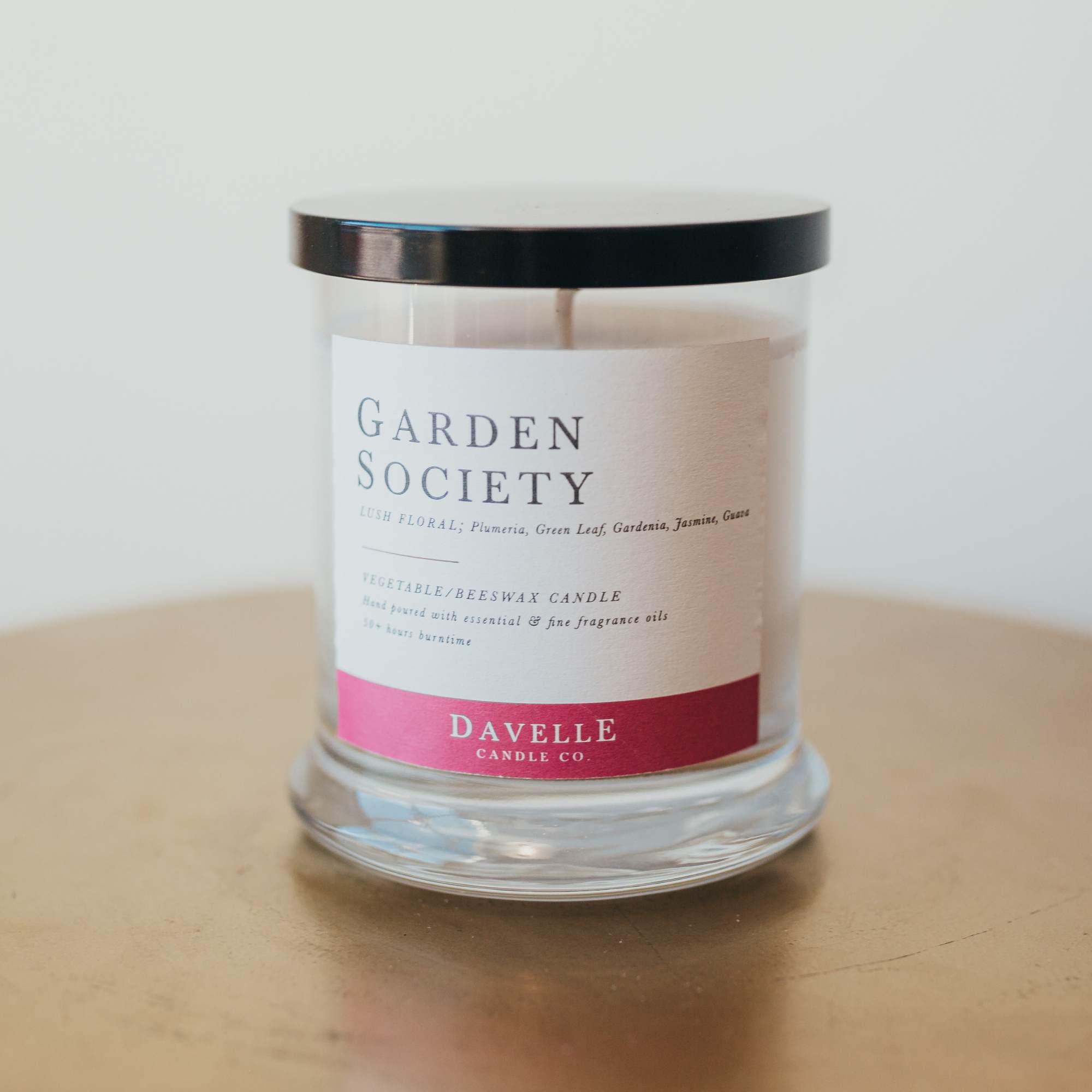 Glass jar candle with a black lid and floral label