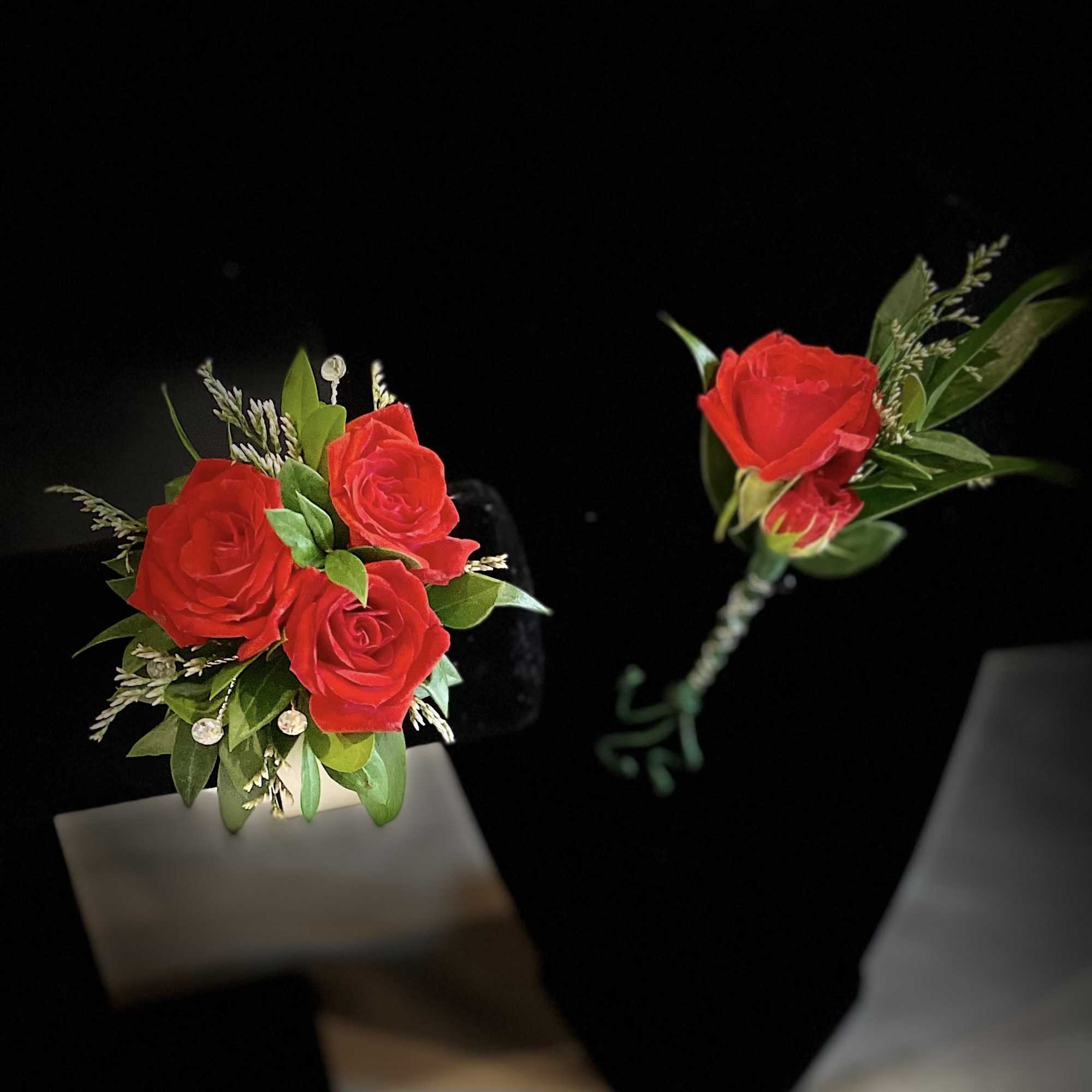 Red rose boutonniere with green foliage on a black background