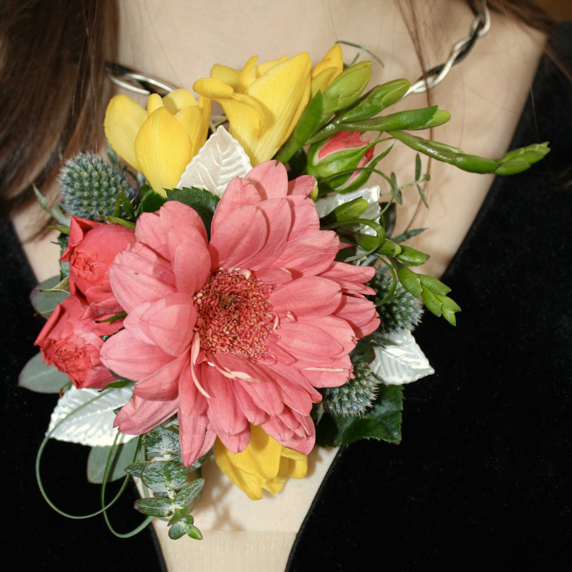 Pink and yellow flower corsage worn on a wrist