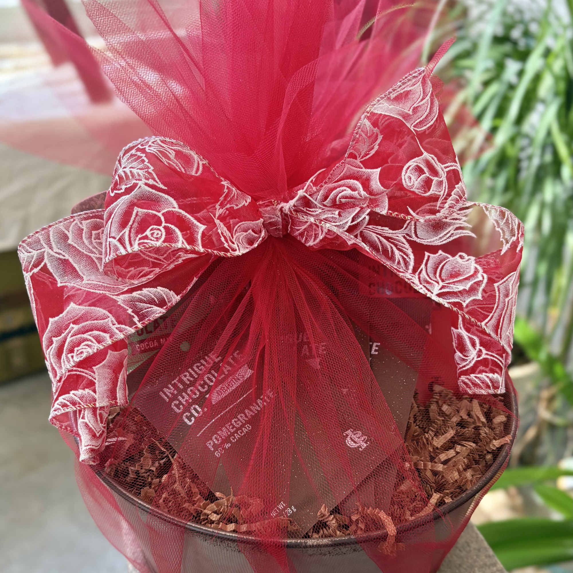 Red gift basket wrapped in tulle with a large bow