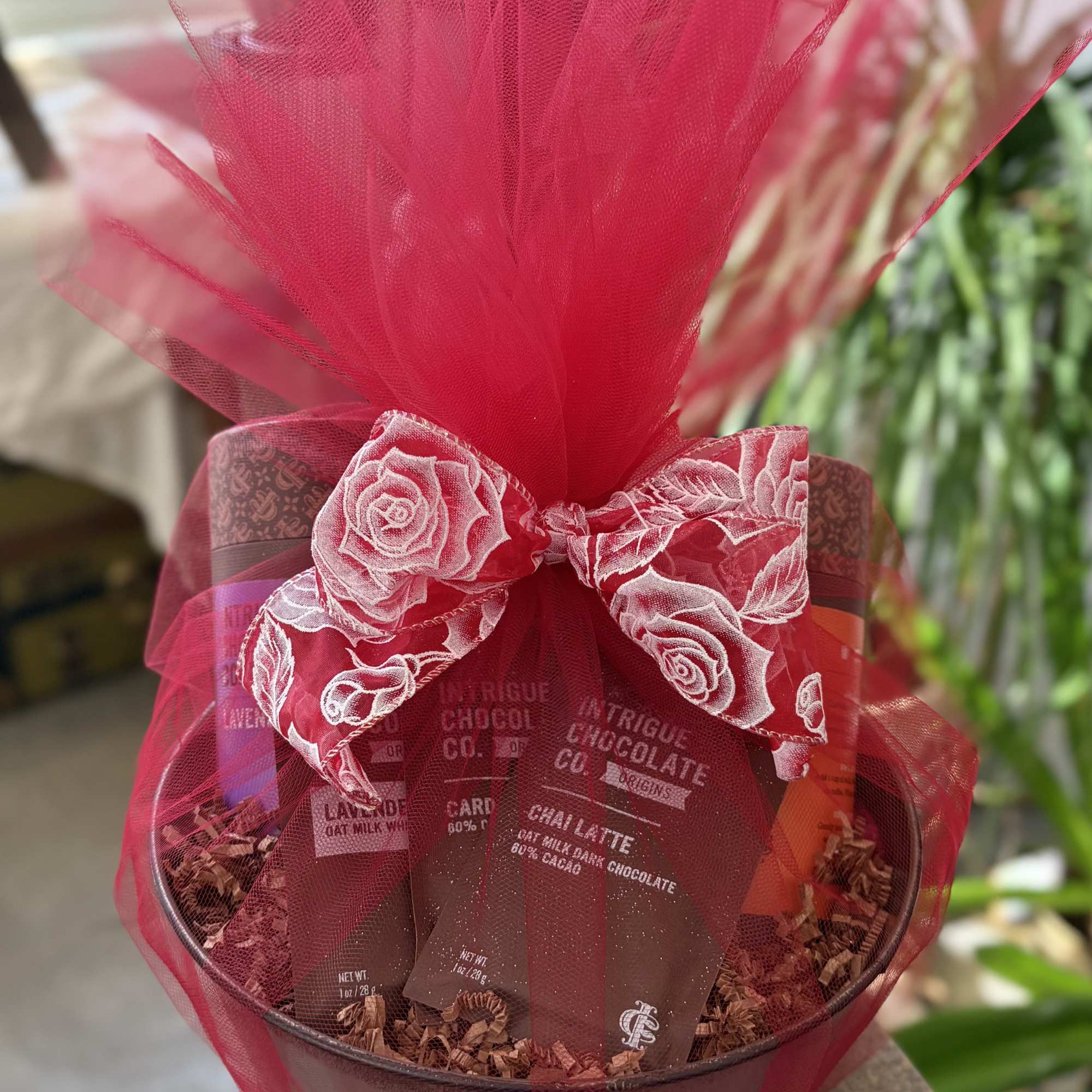 Gift basket of chocolate bars wrapped in red tulle with a decorative bow