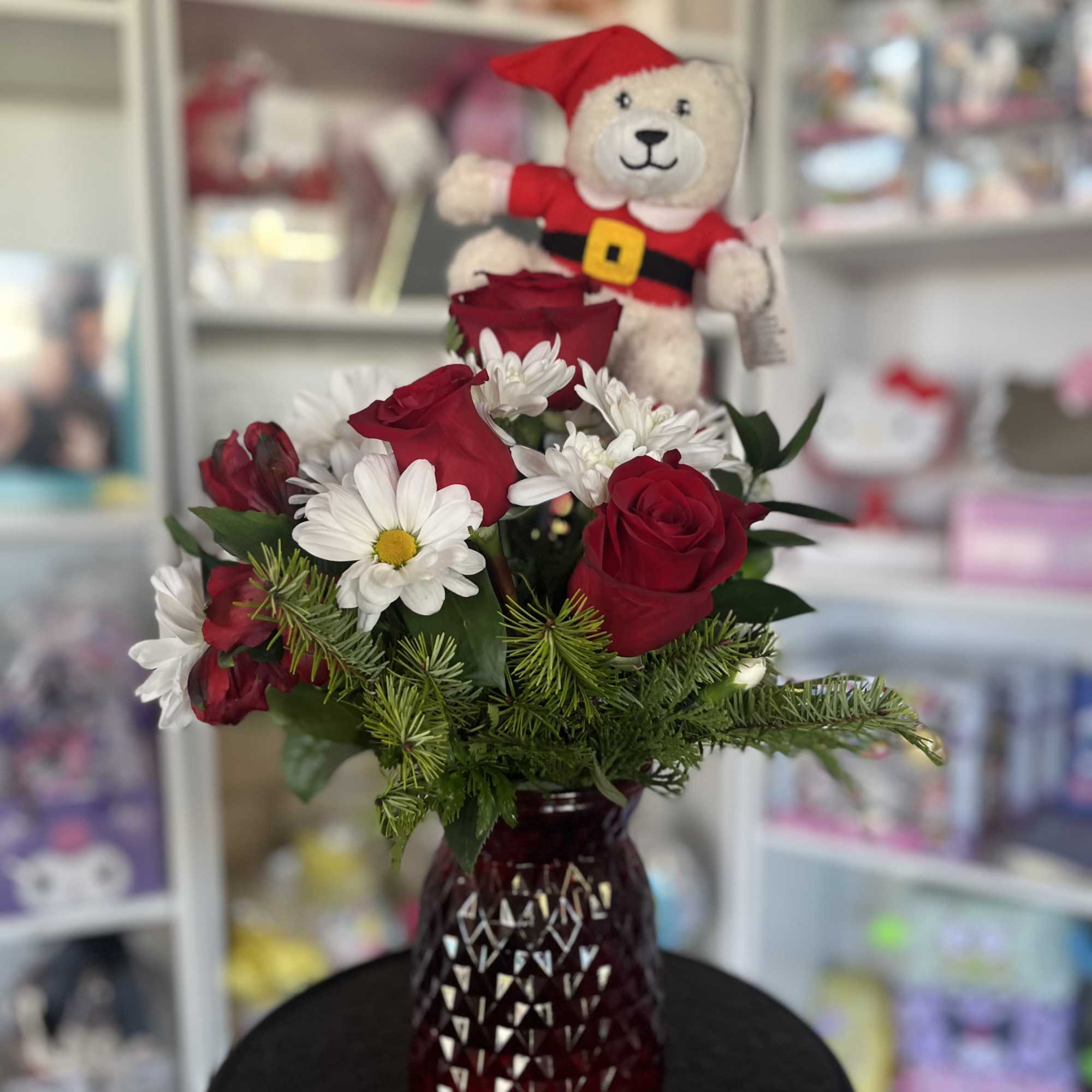 Red roses and white daisies in a red vase with a teddy bear topper