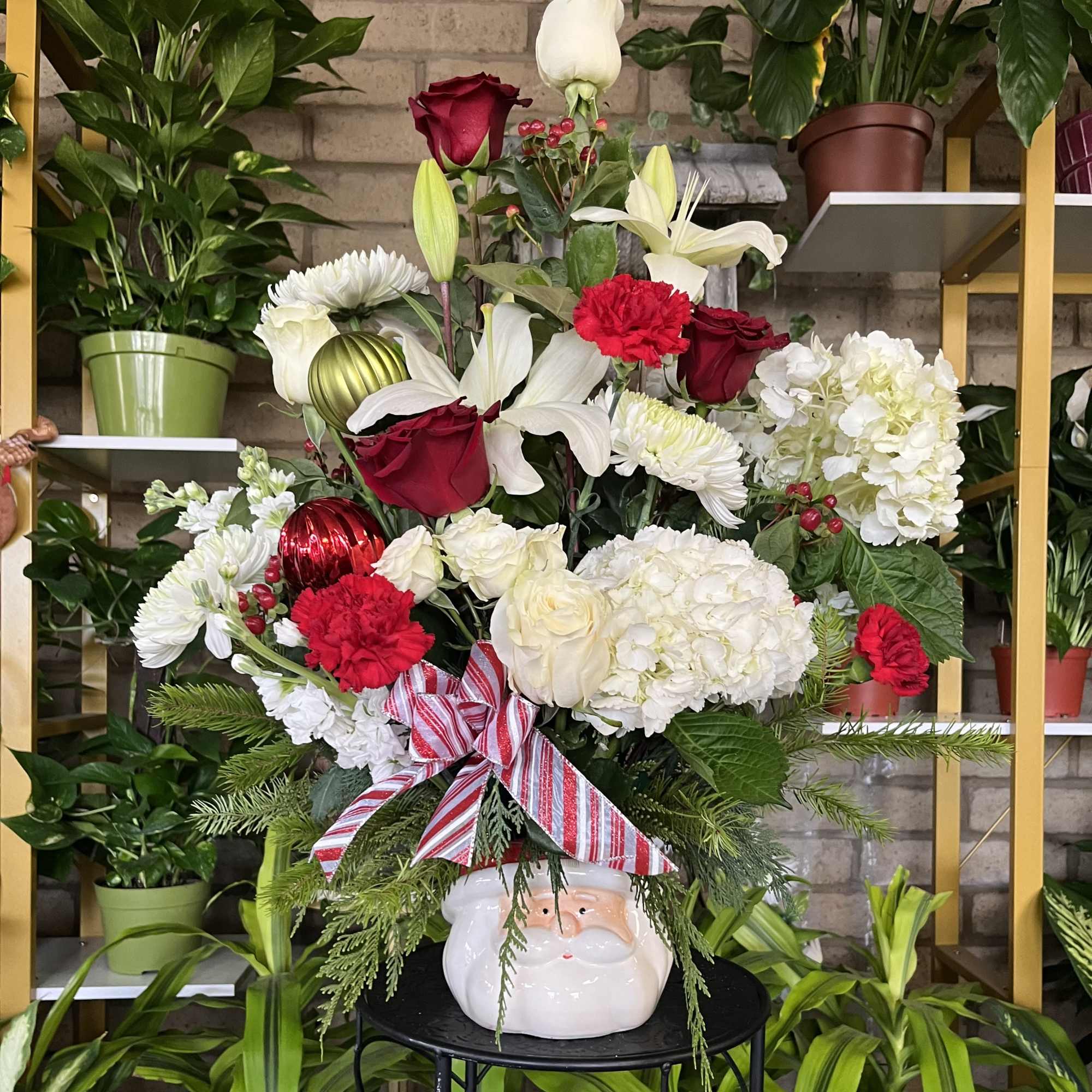 Holiday bouquet in a Santa face vase with red, white, and green flowers