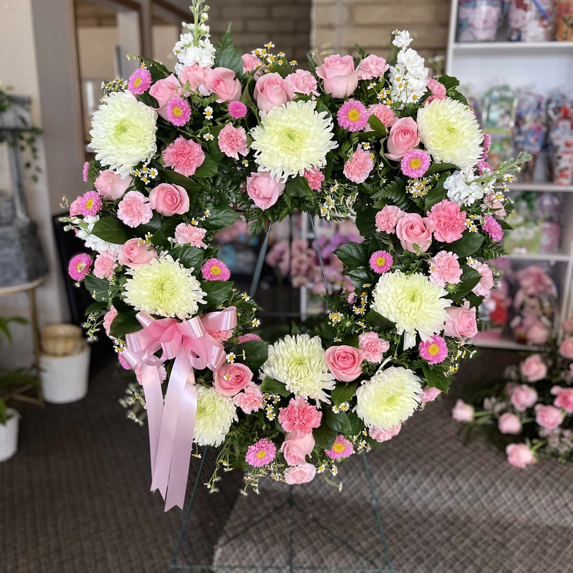 Heart-shaped floral wreath with pink roses and white chrysanthemums on an easel
