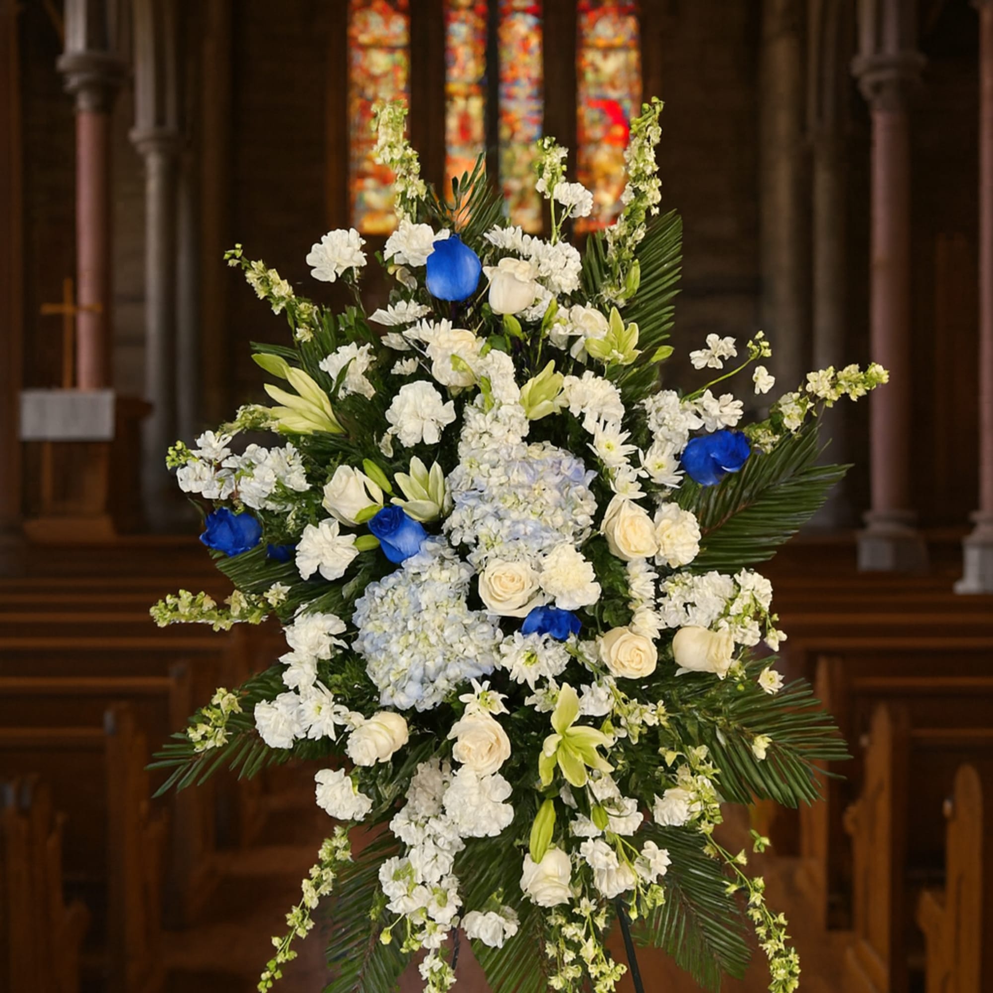 Large white and blue floral standing spray in a church
