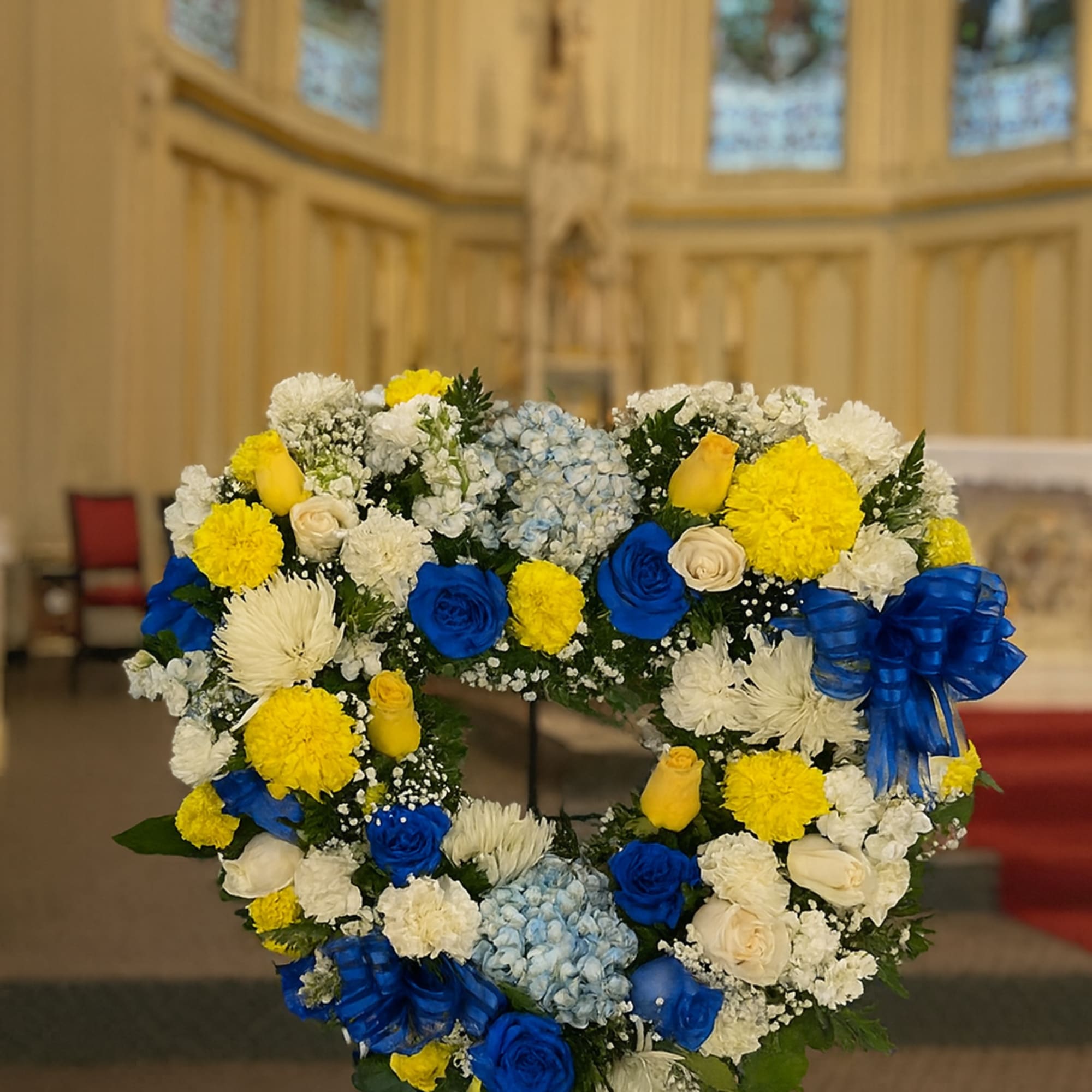 Heart-shaped floral wreath with blue, yellow, and white flowers