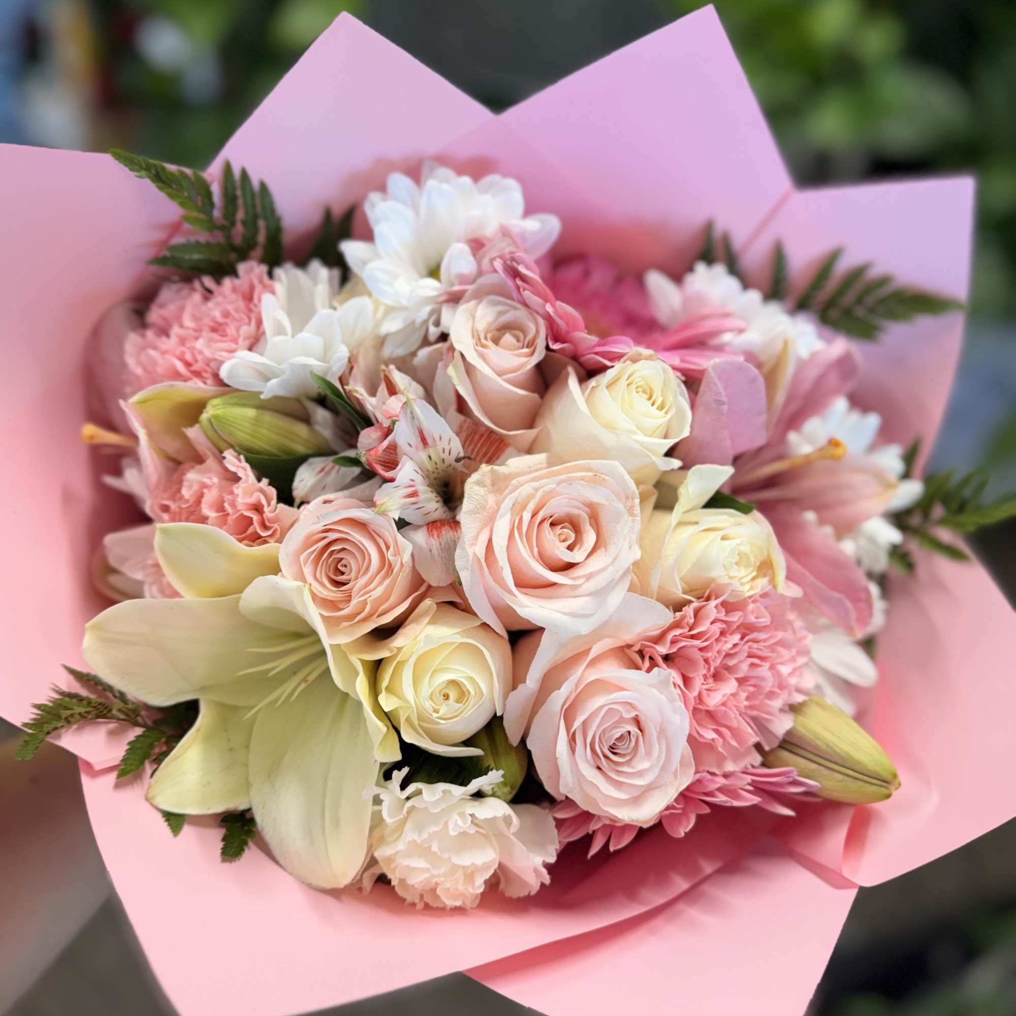 Pink and cream bouquet with roses, lilies, and carnations wrapped in pink paper
