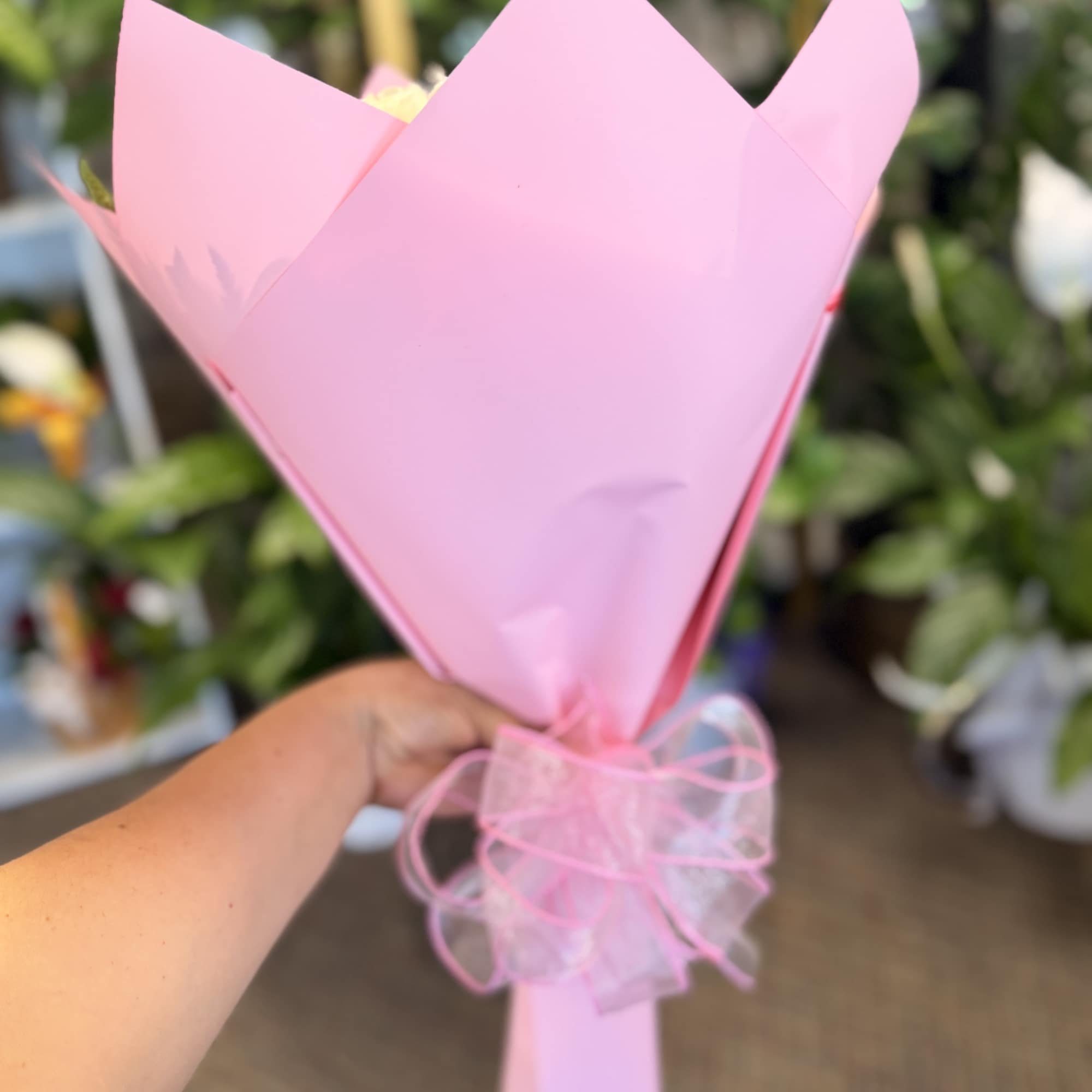 Pink paper-wrapped bouquet with a ribbon tie