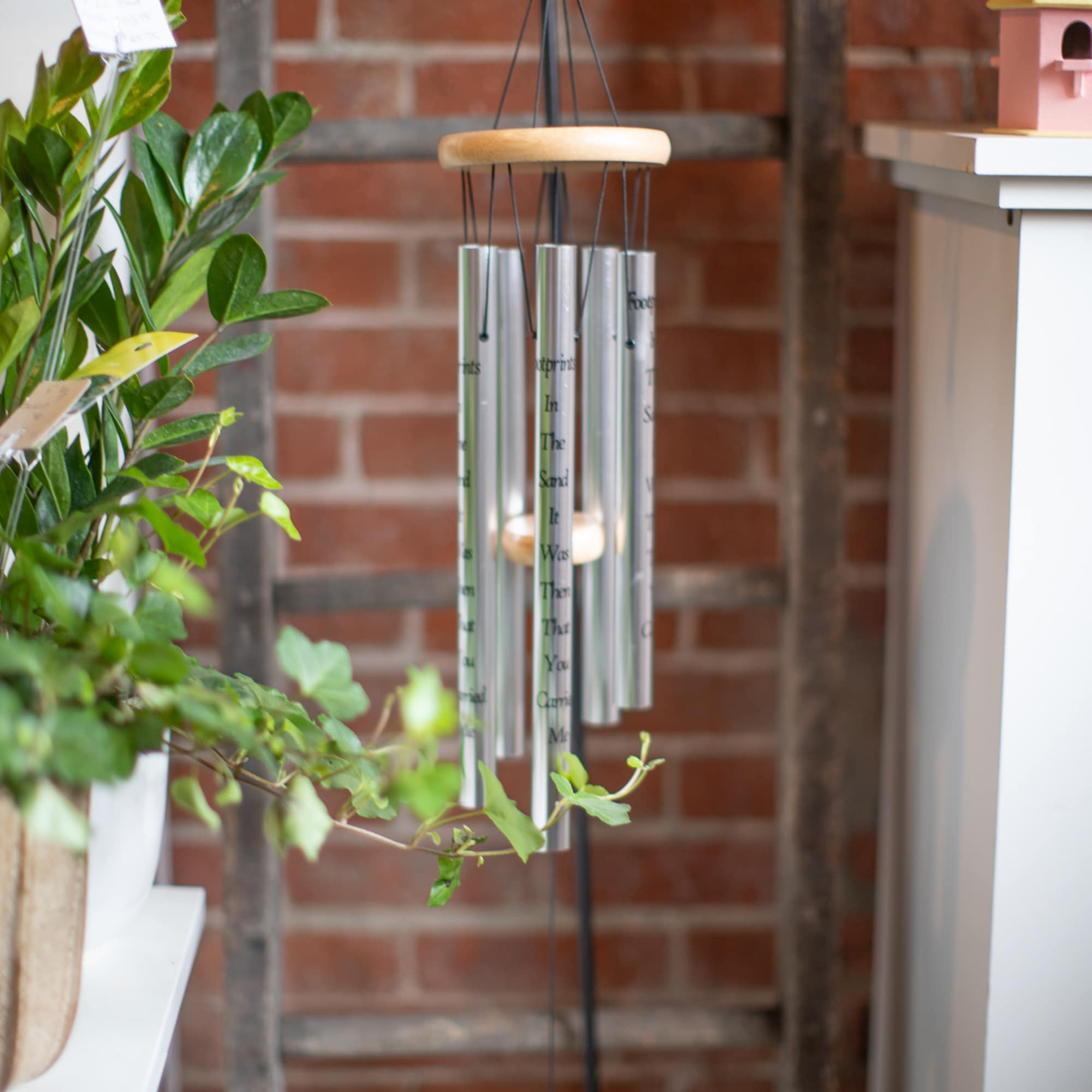 Hanging silver wind chime with a wooden top and black cords