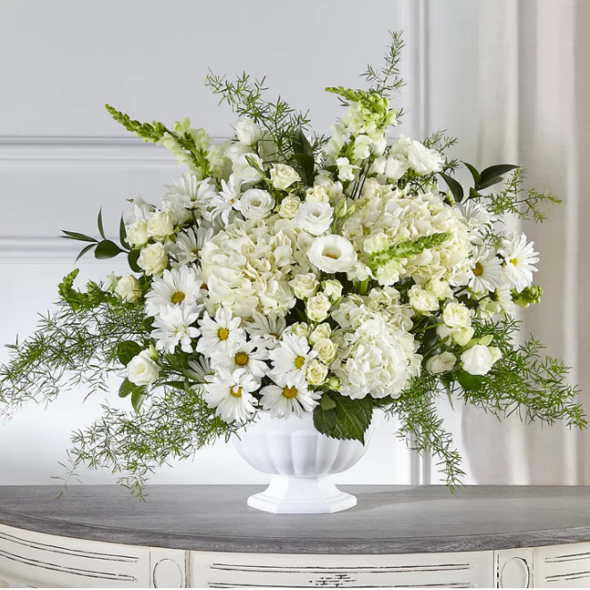 White floral arrangement in a white pedestal vase