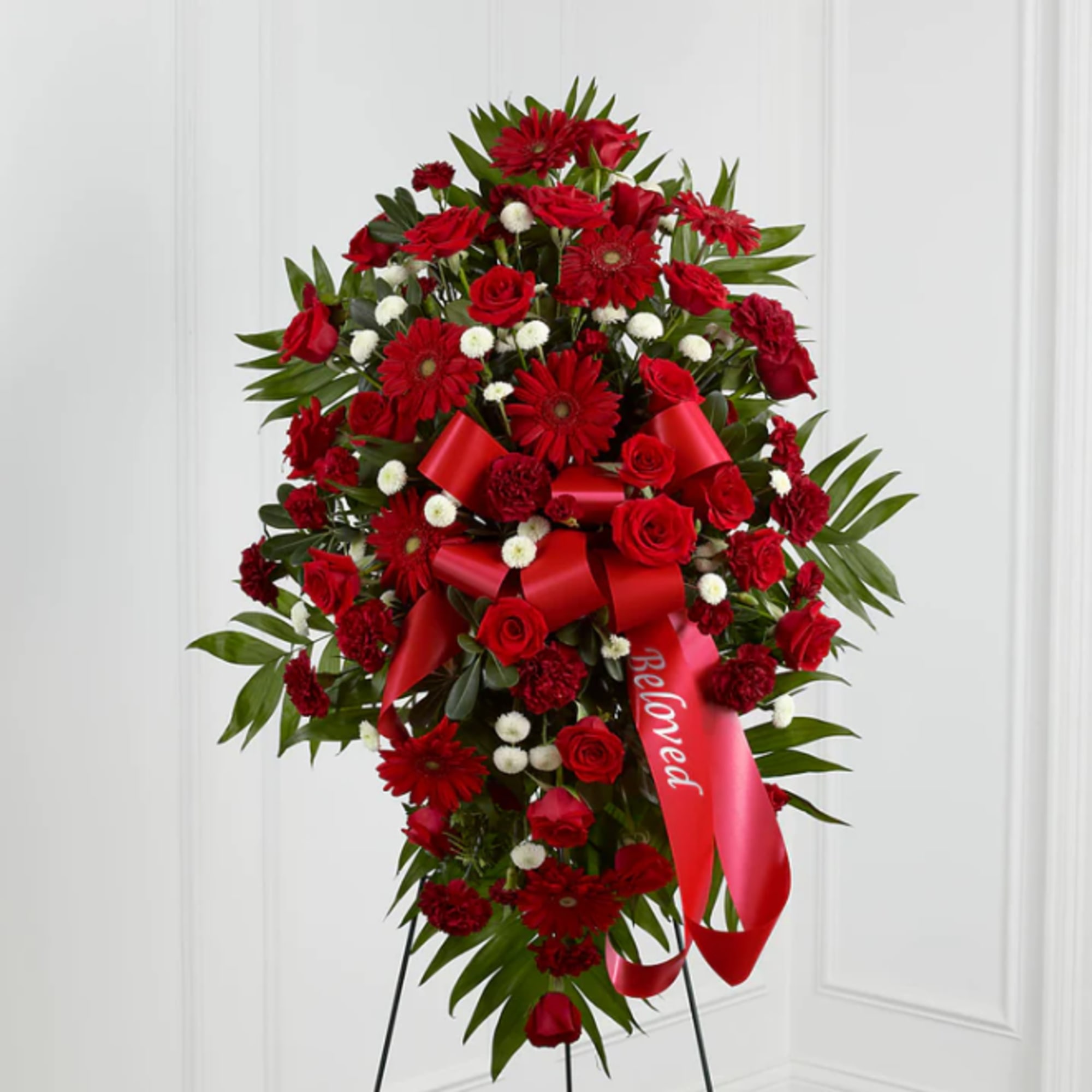Standing red floral spray with roses and gerbera daisies on a ribboned easel