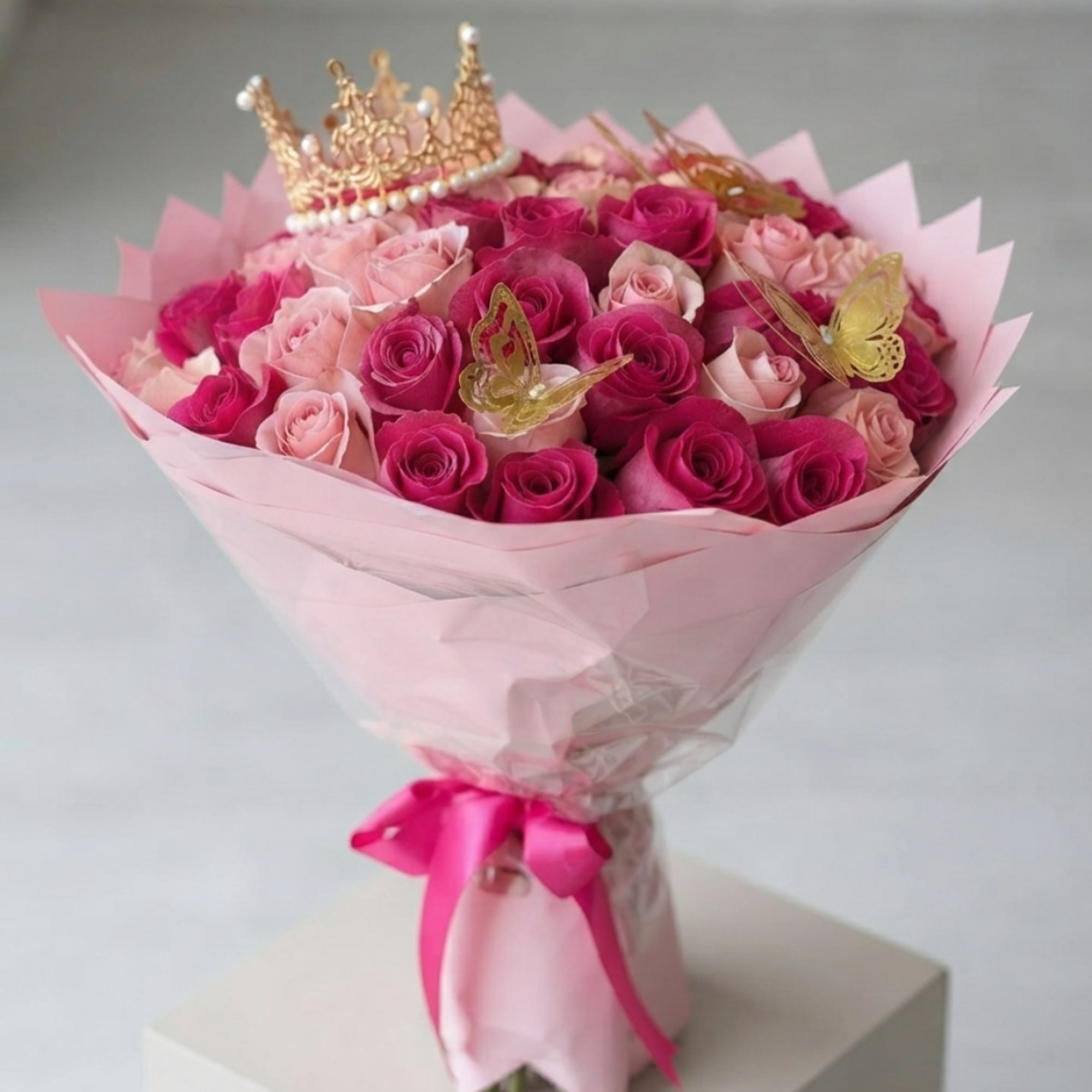 Pink and blush rose bouquet with a gold crown topper and butterfly decorations