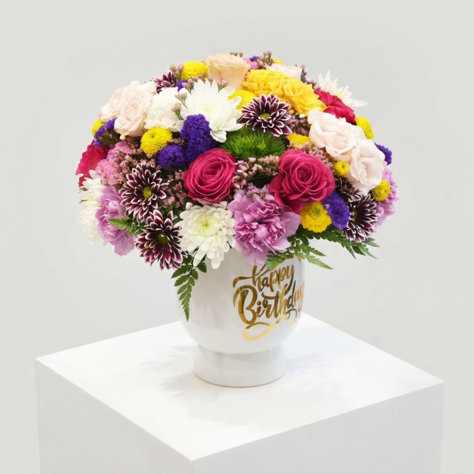 Colorful mixed flower arrangement in a white vase with a birthday message
