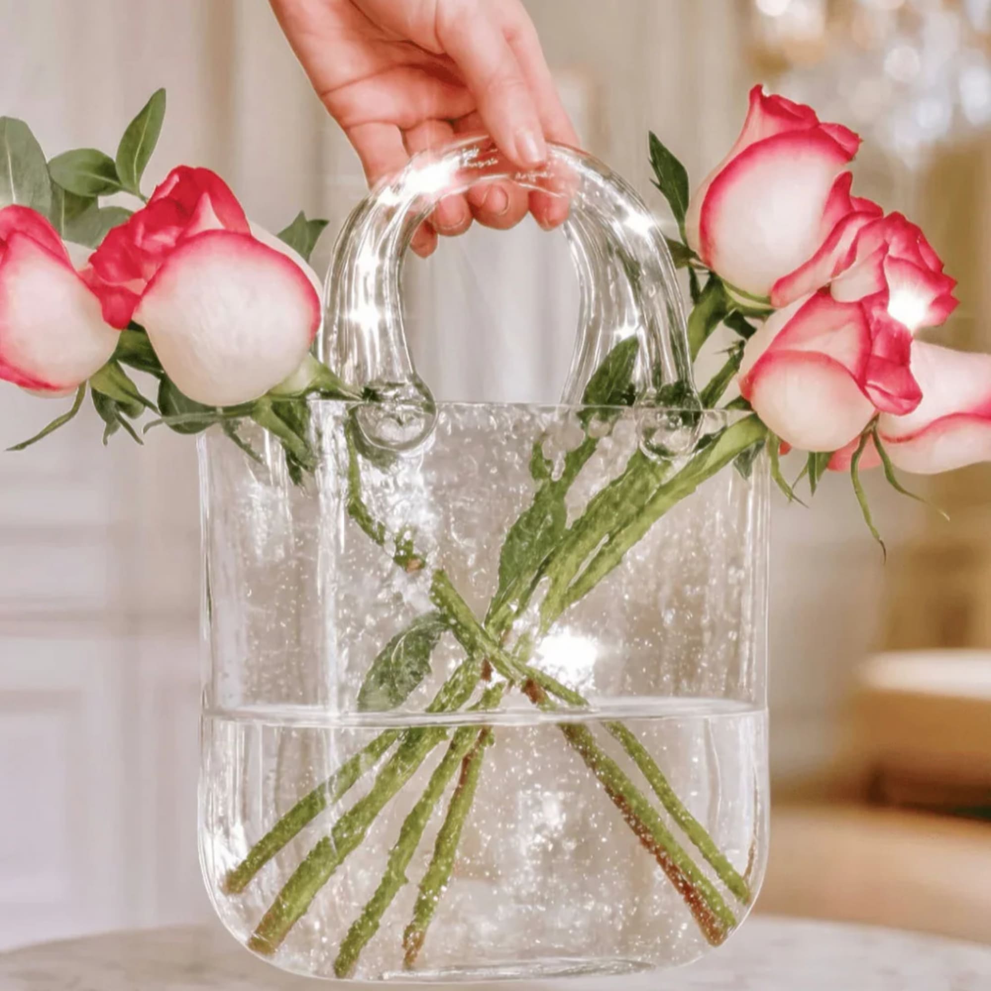 Pink and white roses arranged in a clear handbag-shaped vase