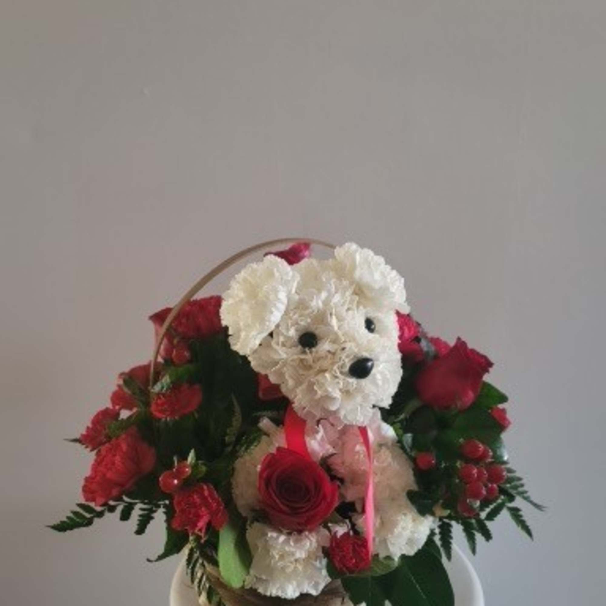 White teddy bear surrounded by red roses in a basket