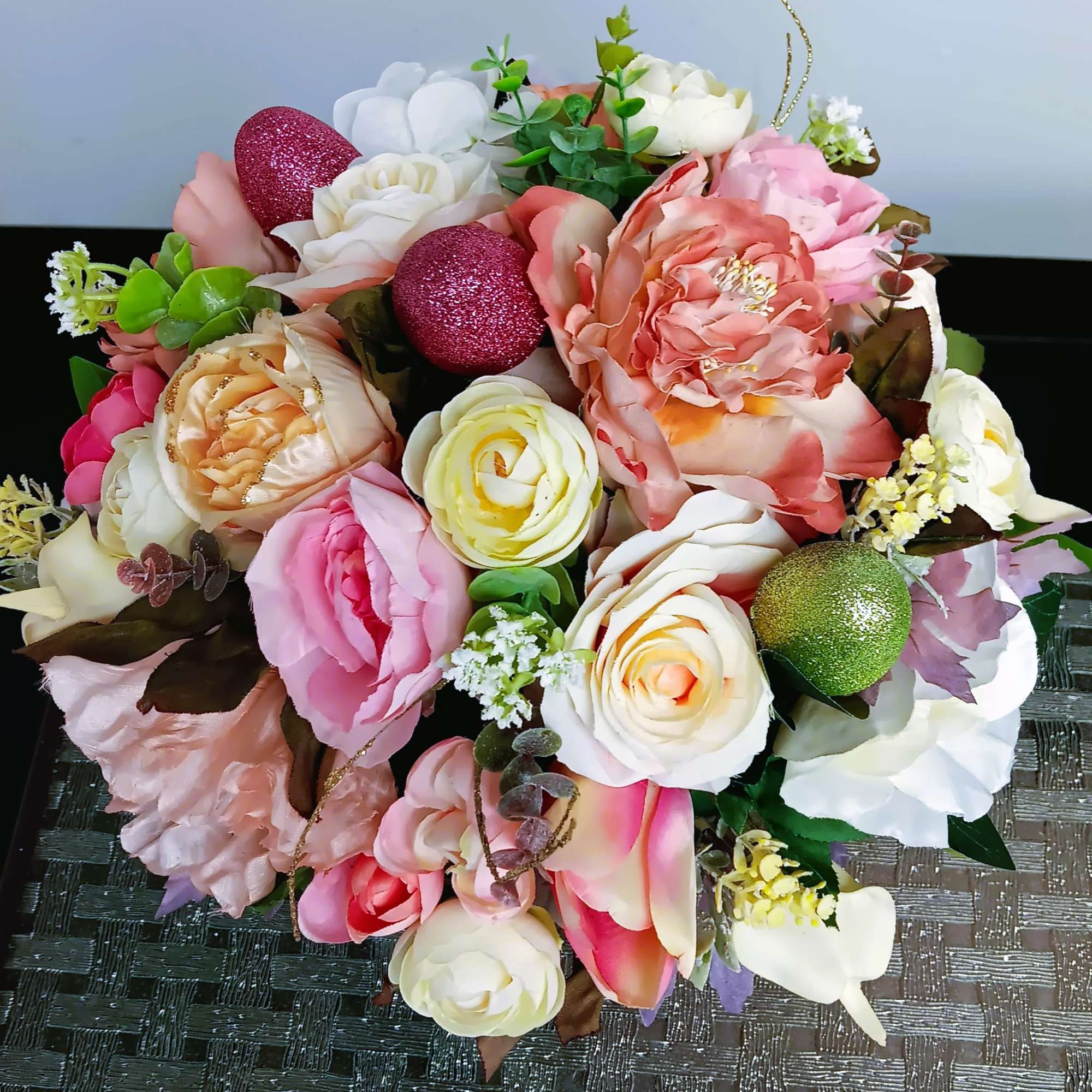 Round silk arrangement of peach, pink, and cream roses with glittered egg accents