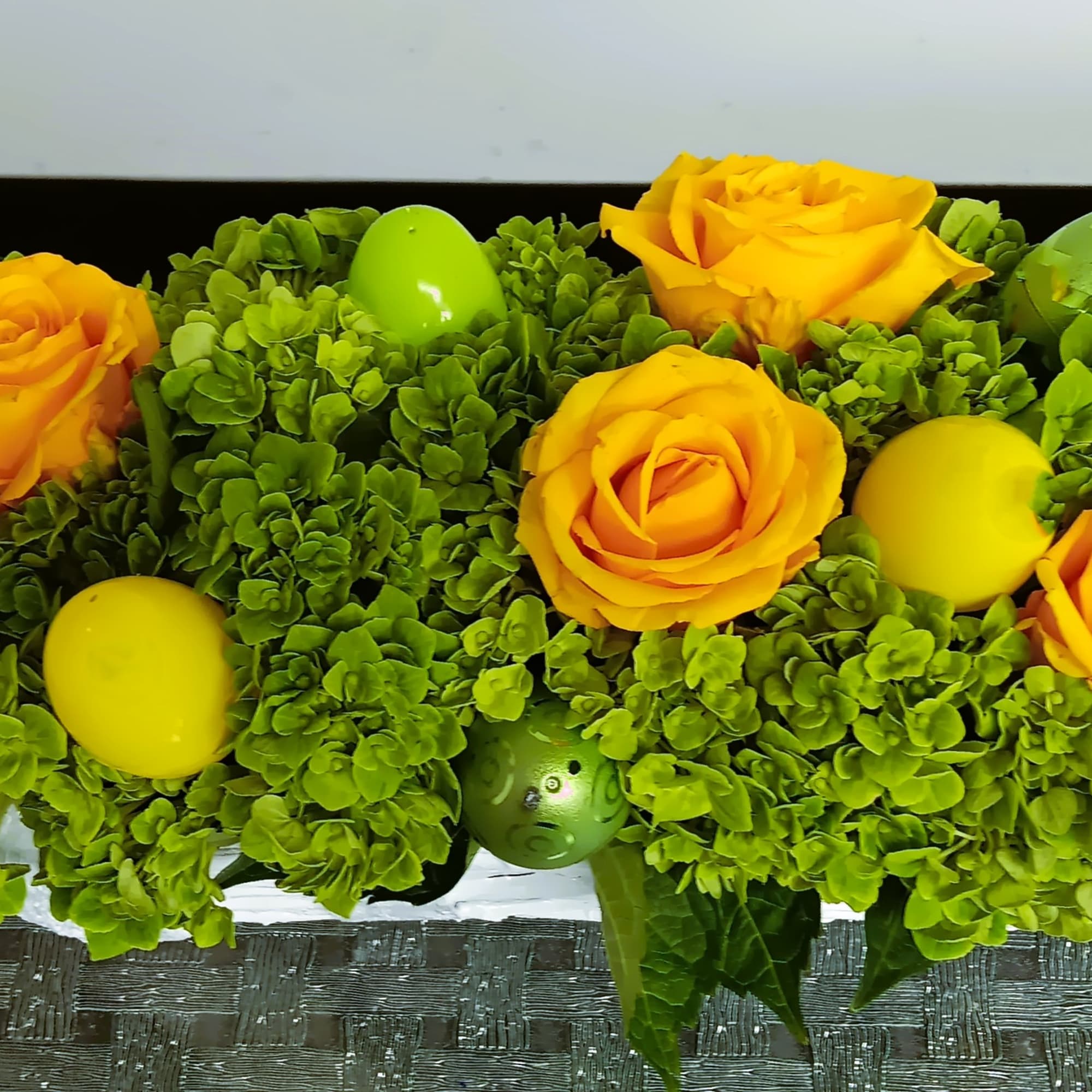Yellow roses in a green hydrangea arrangement with decorative eggs