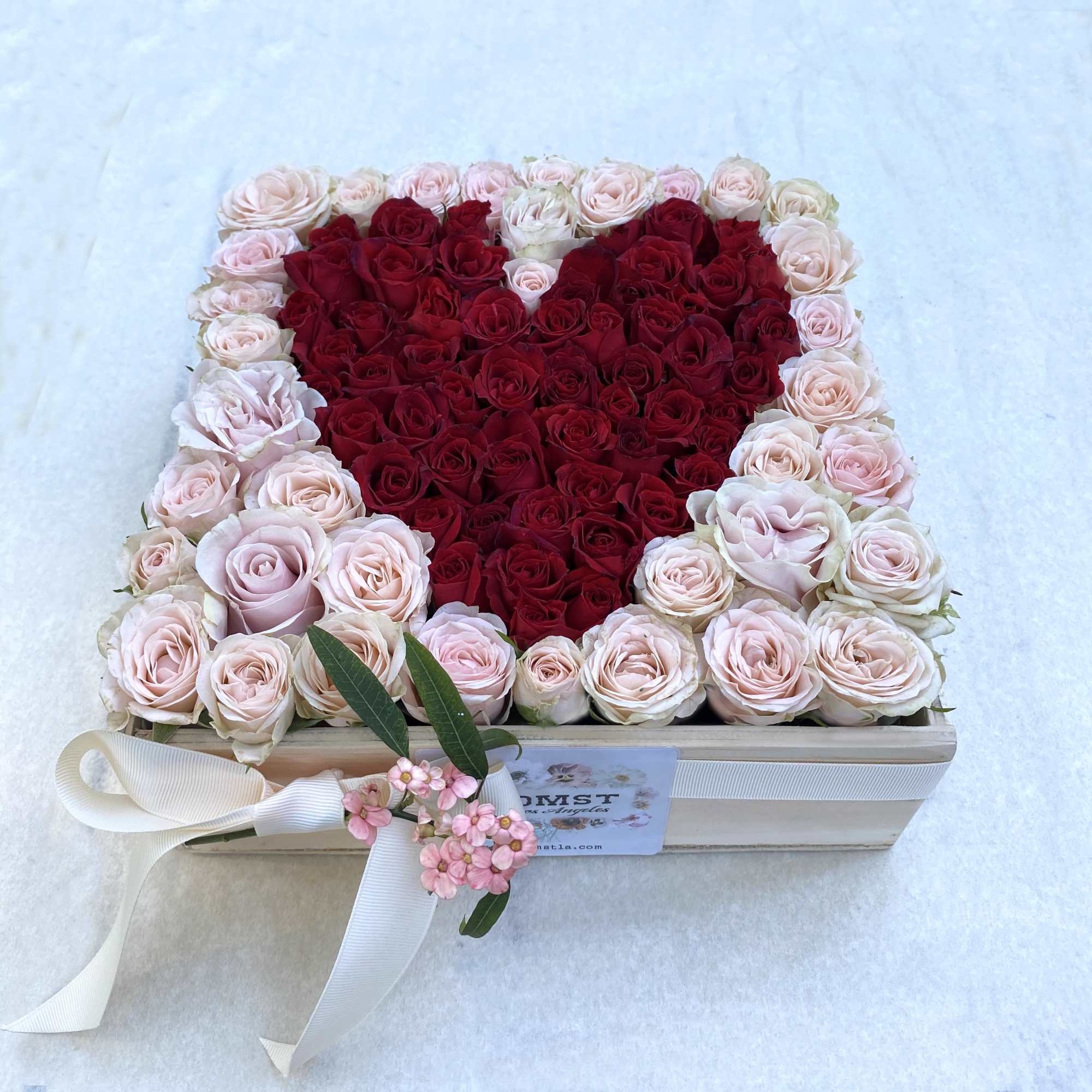 Heart-shaped rose arrangement in a wooden box with a ribbon bow