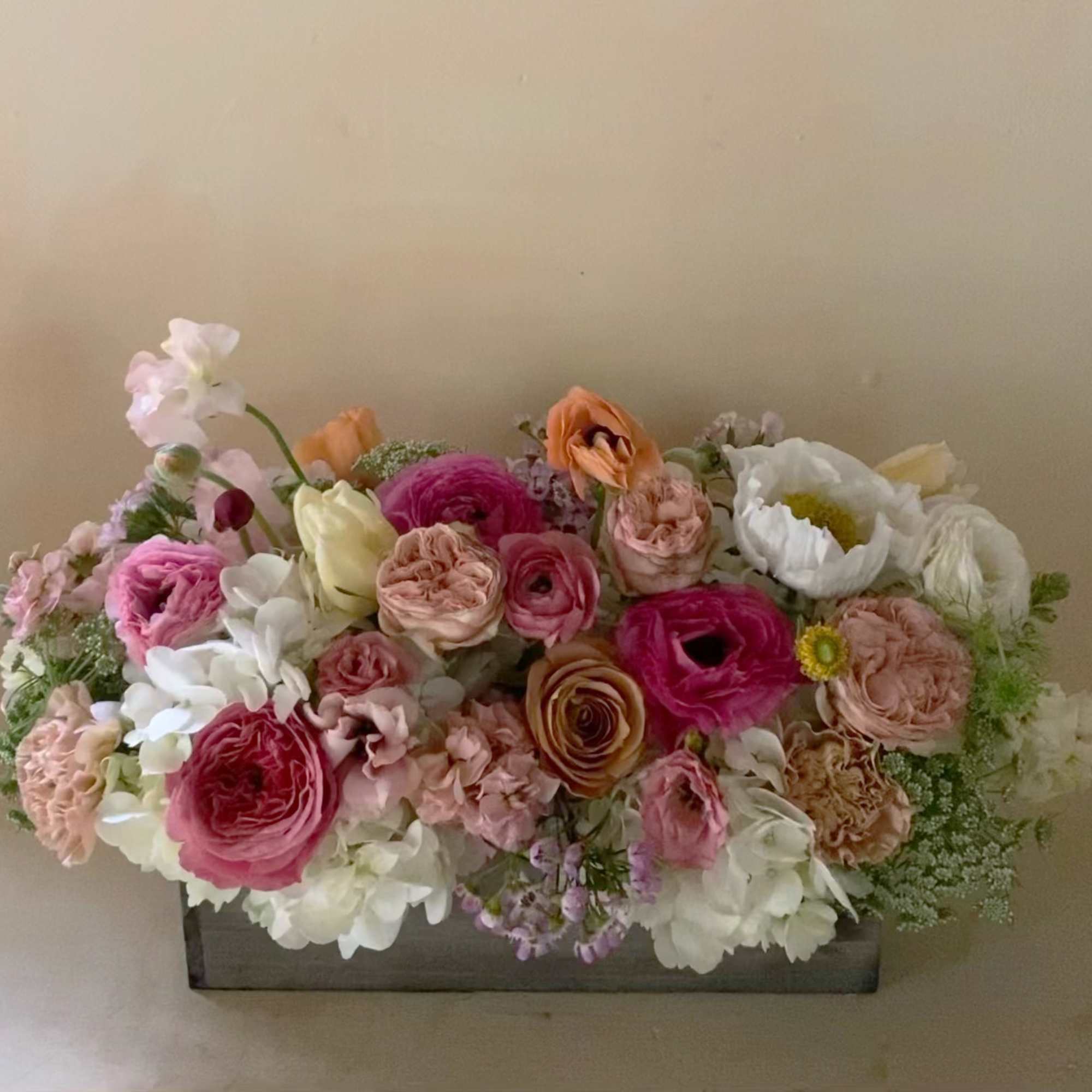 Mixed pink, white, and peach flowers arranged in a rectangular box