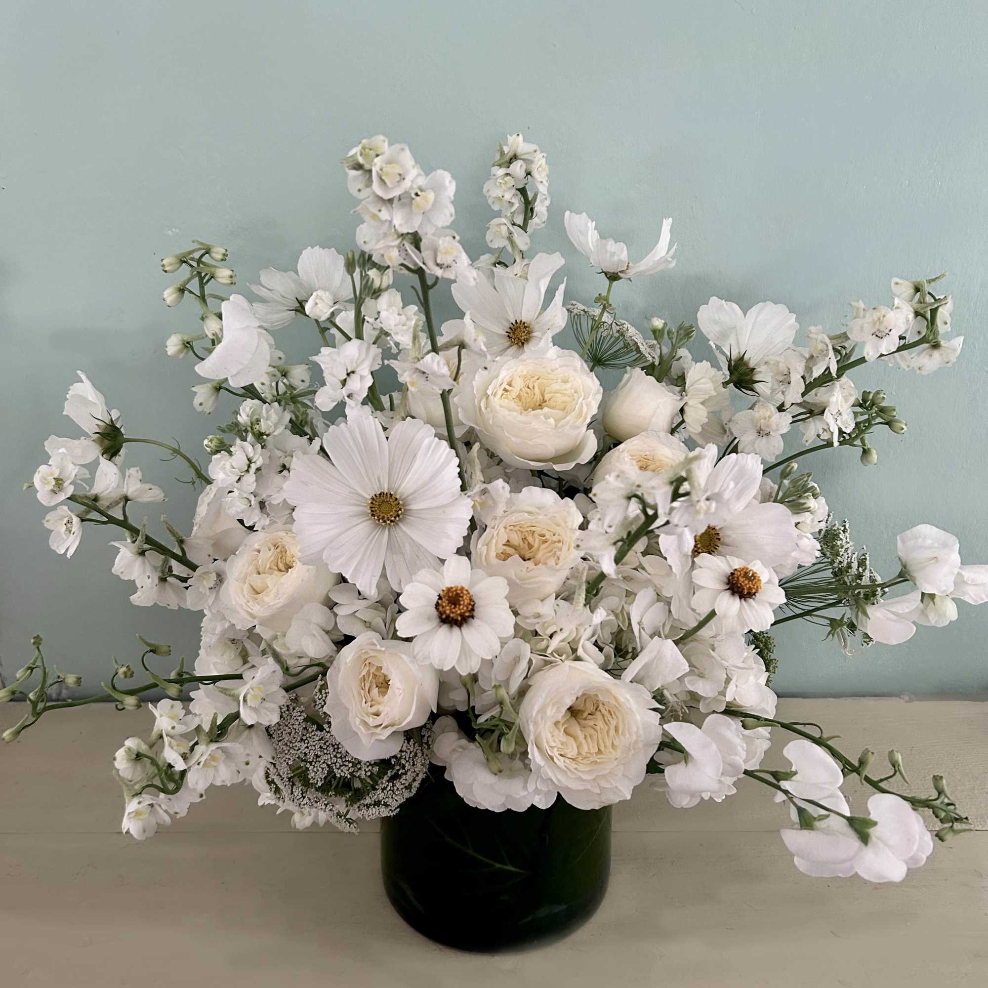 White floral arrangement in a dark vase with airy blooms