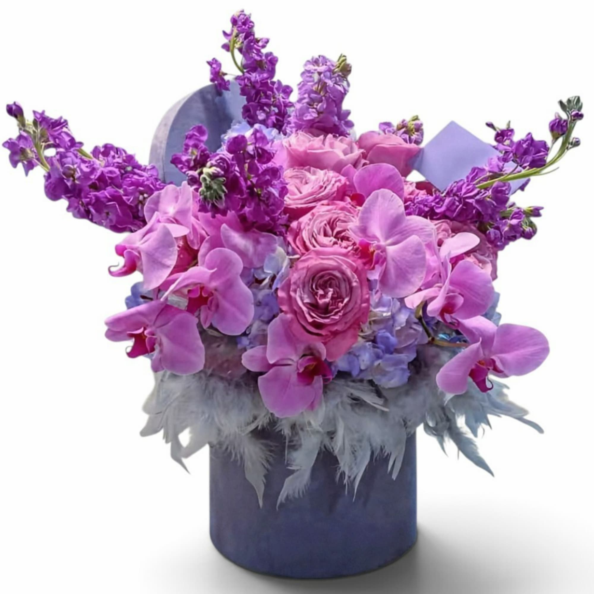 Pink roses and purple orchids arranged in a blue hatbox