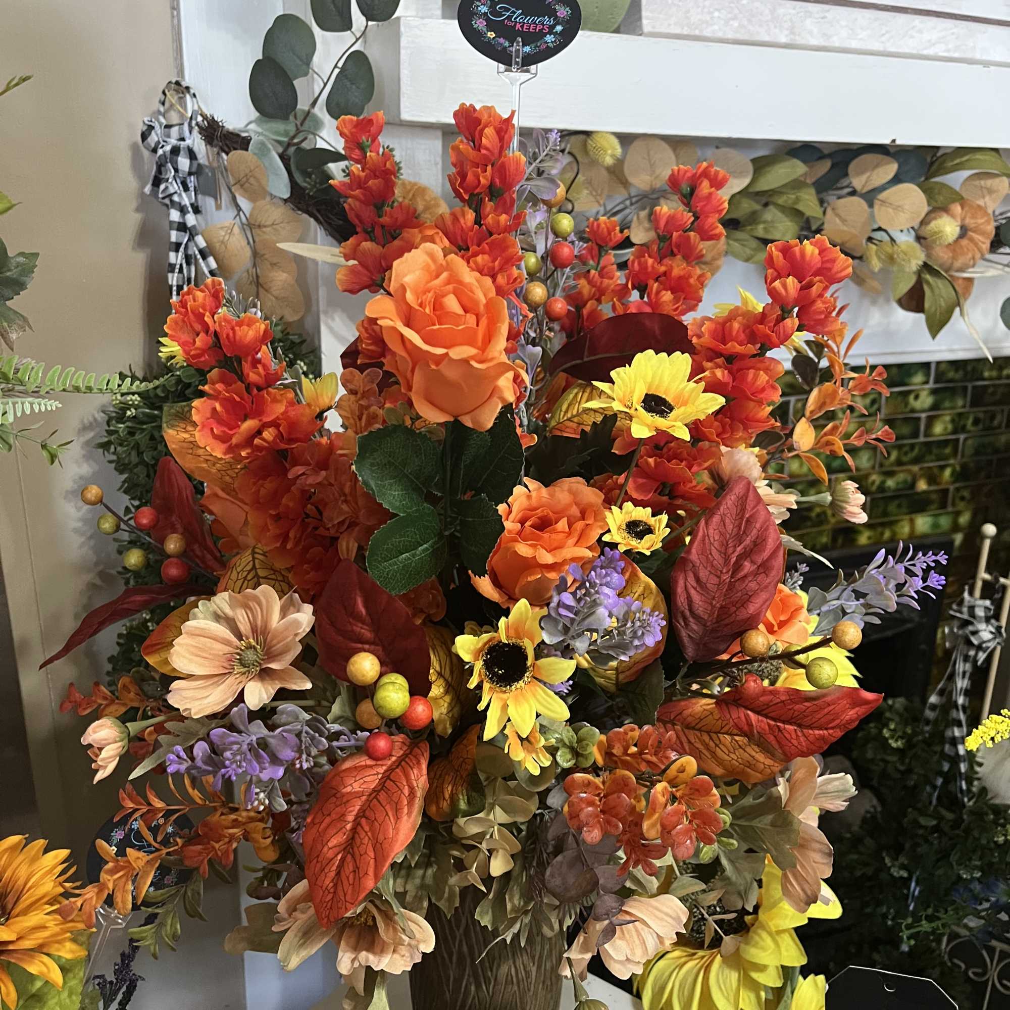 Autumn floral arrangement with orange, yellow, and peach blooms in a brown vase