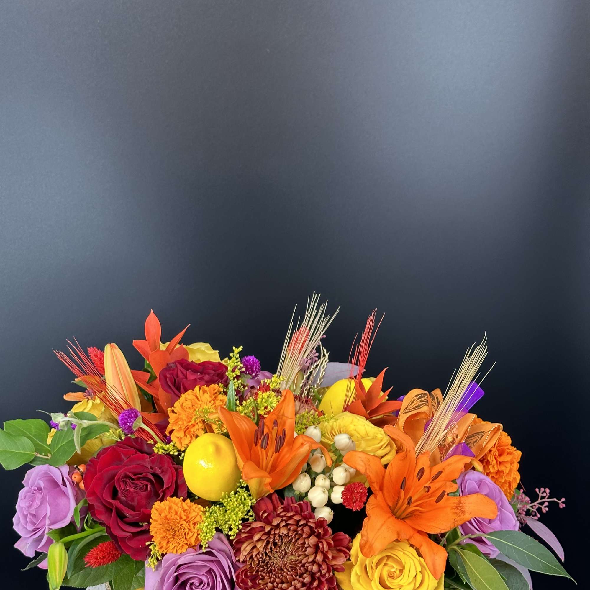 Colorful mixed bouquet with roses, lilies, and chrysanthemums in a low container