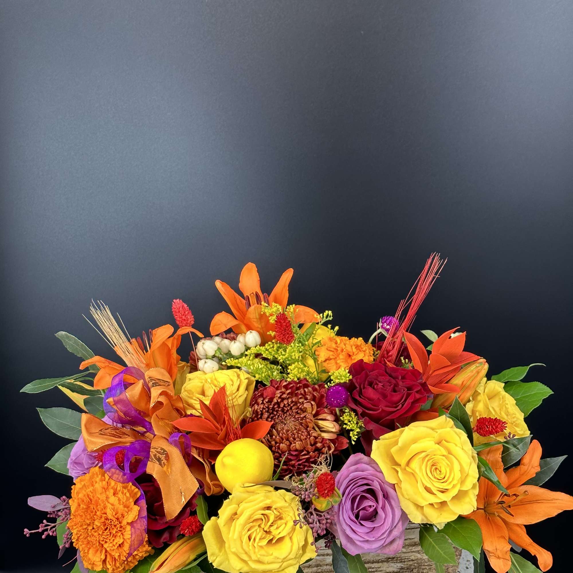 Bright mixed bouquet with roses, chrysanthemums, and orange lilies in a low container
