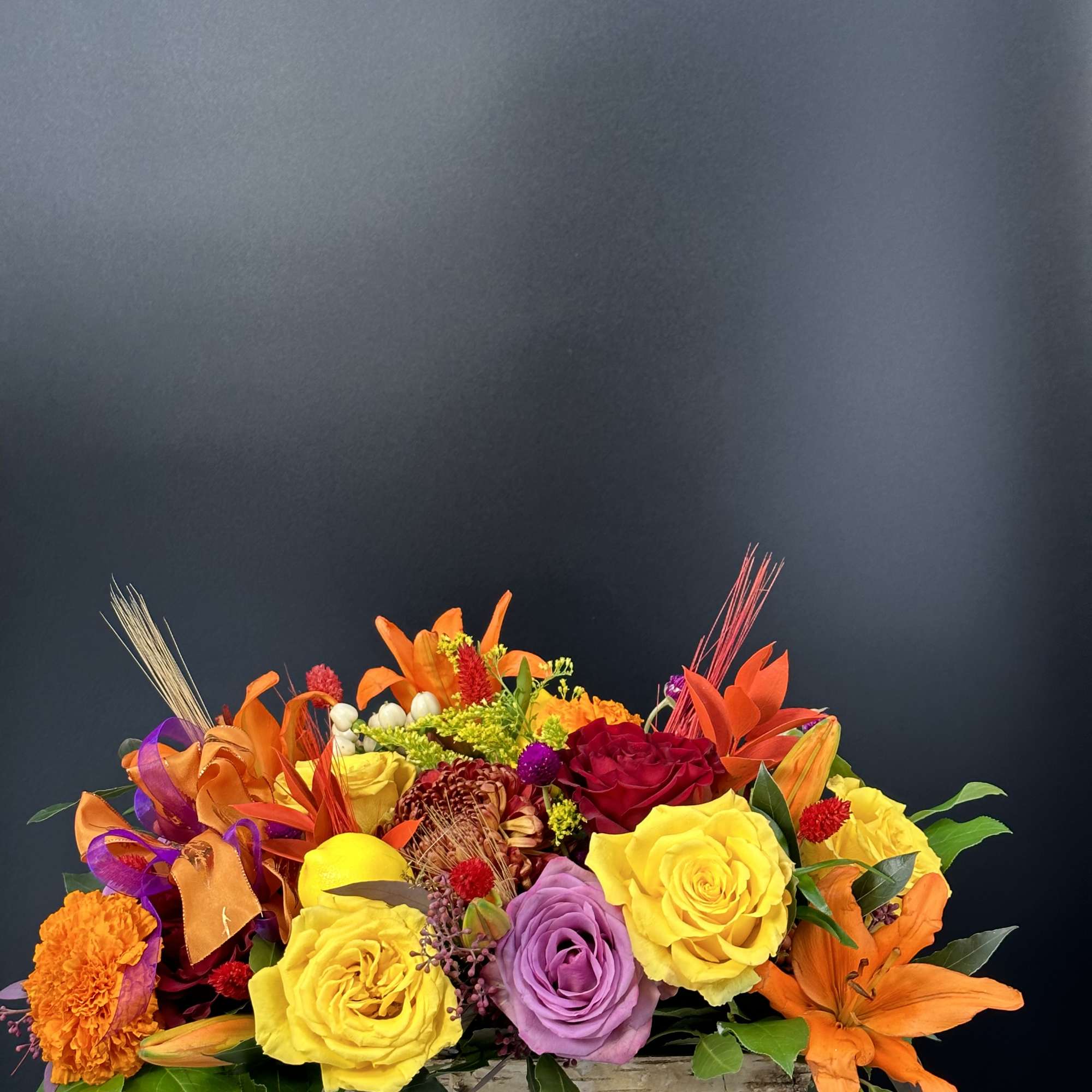 Bright mixed bouquet in a rustic wooden container with orange lilies and roses