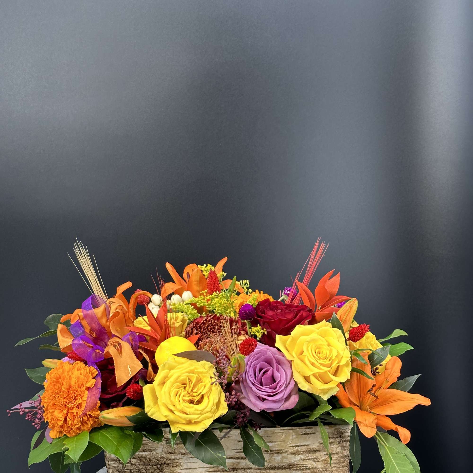 Bright mixed flower arrangement in a rustic rectangular wooden container