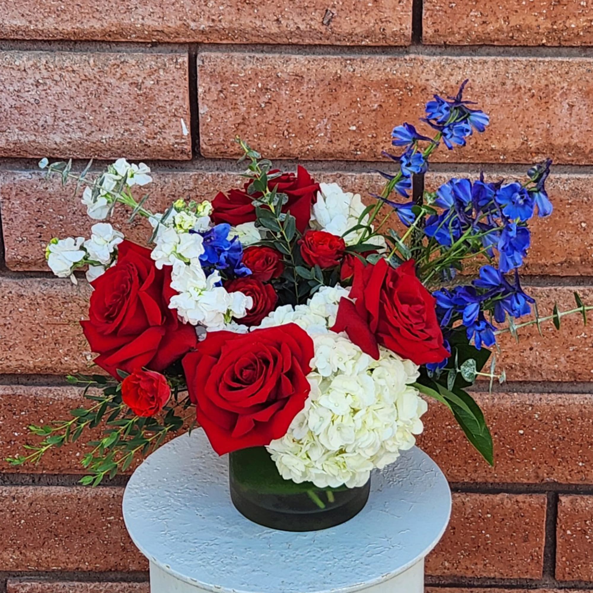 Red roses, white hydrangeas, and blue flowers in a dark vase