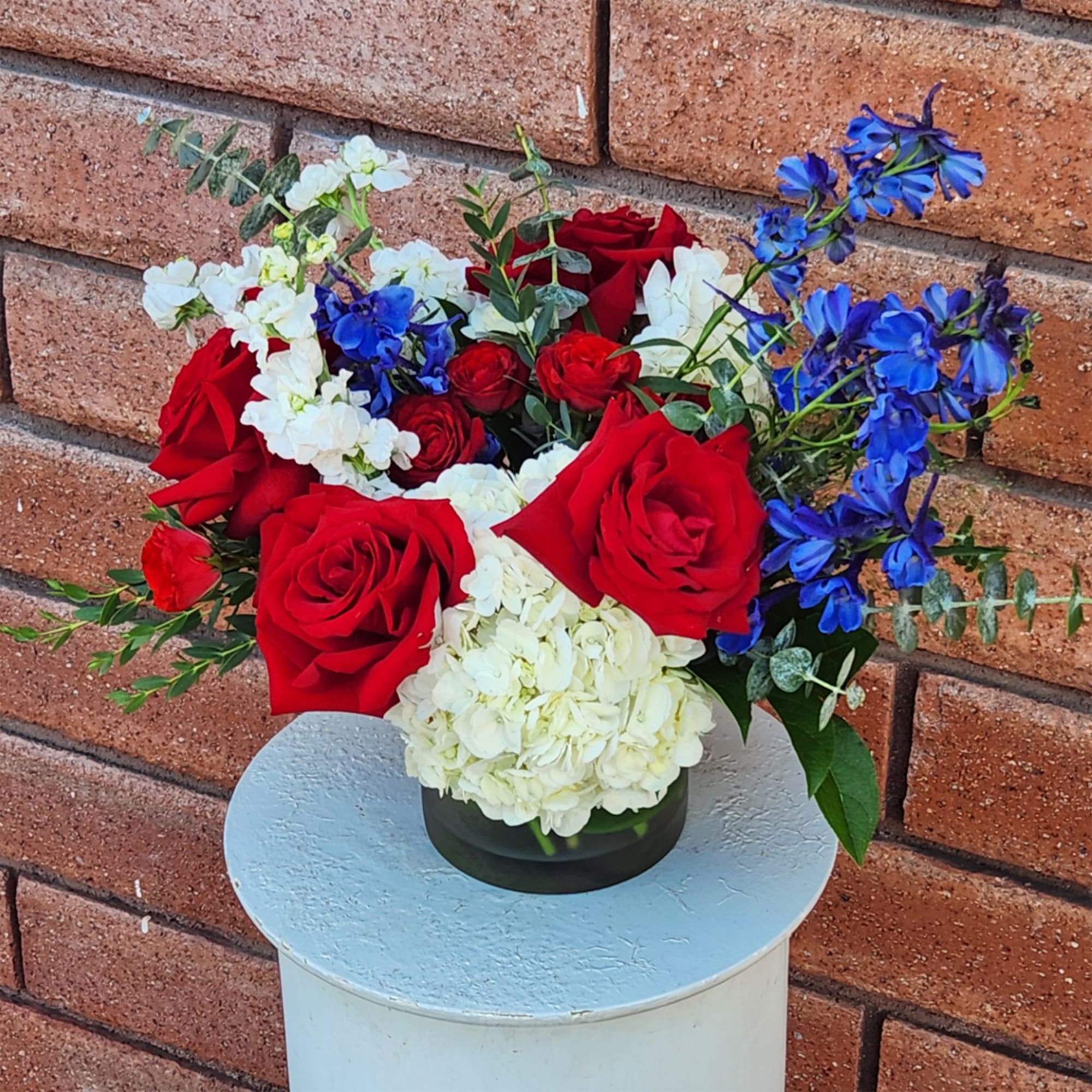 Red roses with white hydrangeas and blue flowers in a black vase