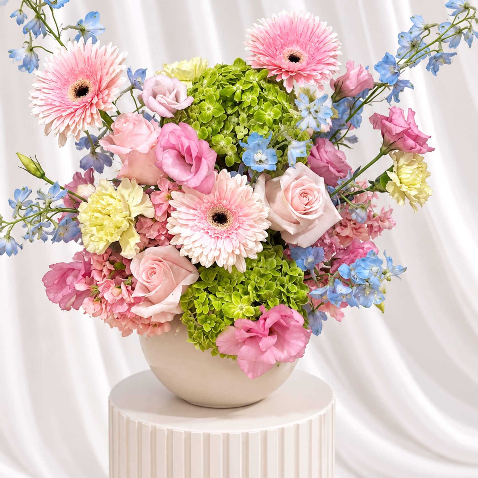 Pink and blue mixed flower arrangement in a round vase