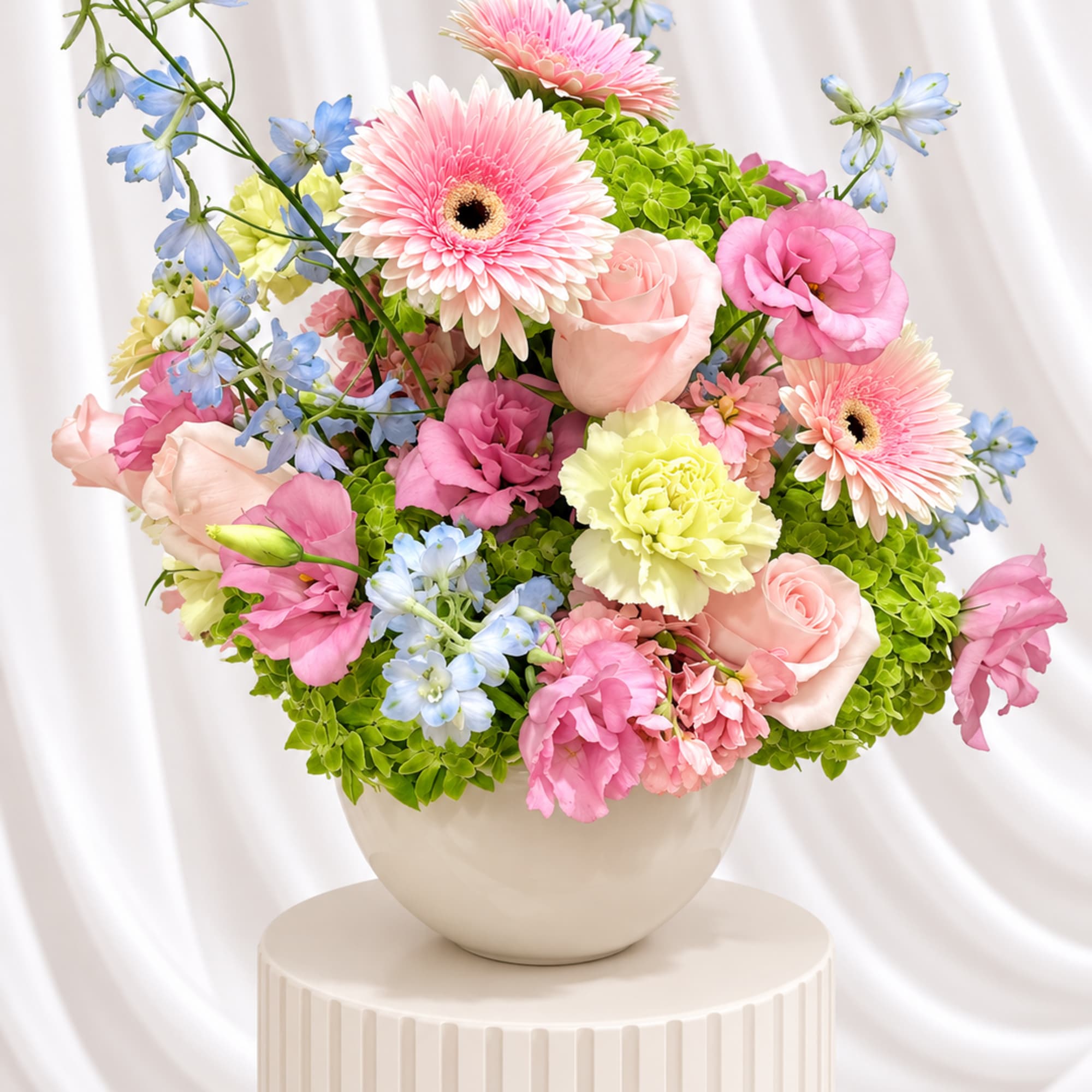 Pink and blue mixed flower arrangement in a white vase